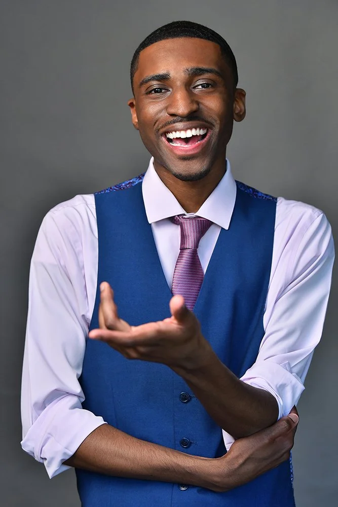 Actor headshot mid-gesture with a warm, expressive smile