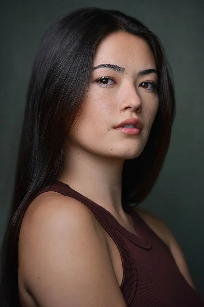 Cinematic actor headshot of a woman turned partly away from the camera and looking back over her shoulder