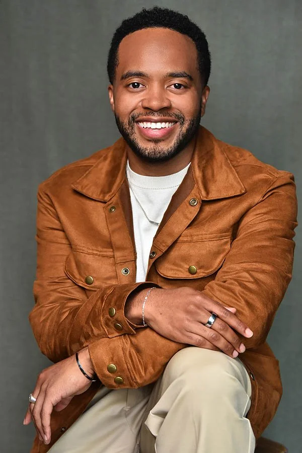 A professional corporate headshot of a smiling businessman in a stylish brown suede jacket, taken by a Los Angeles business portrait photographer.