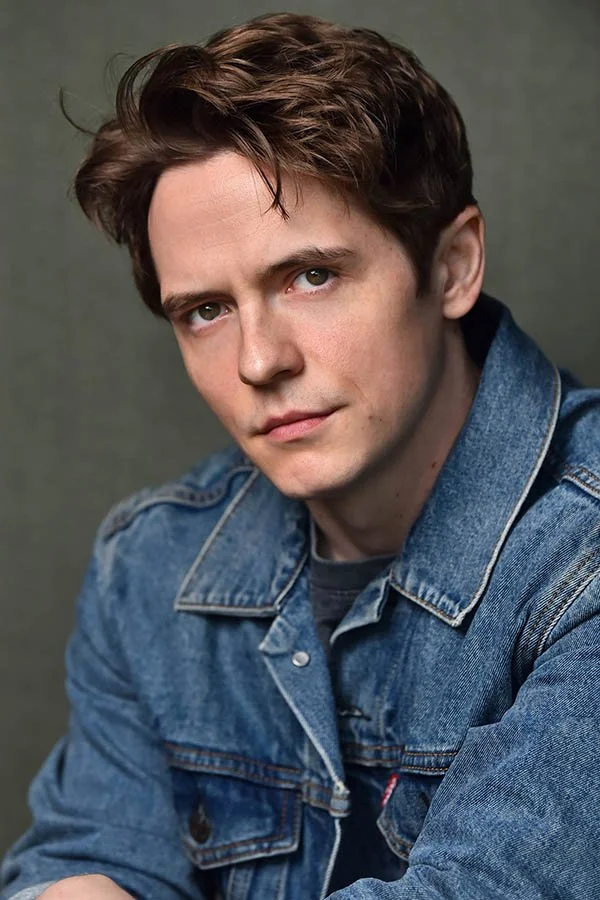 An edgy, cinematic theatrical headshot of a male actor wearing a denim jacket, featuring intense, grounded direction and expert lighting. This portrait showcases character depth and raw intensity, designed by Marc Cartwright to stand out in the Los A