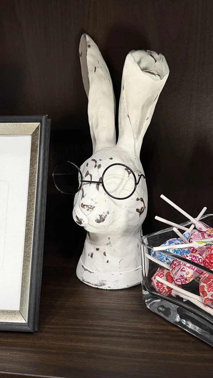 A bespectacled ceramic rabbit figure on a shelf at Lucky Rabbit Self Tapes, part of the studio's branded waiting area decor.