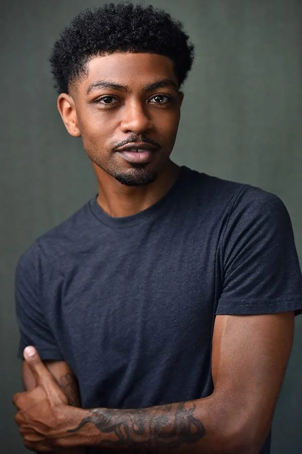 Dramatic theatrical headshot of a male actor in a black t-shirt with a textured green background, editorial actor portrait by Marc Cartwright in Los Angeles.