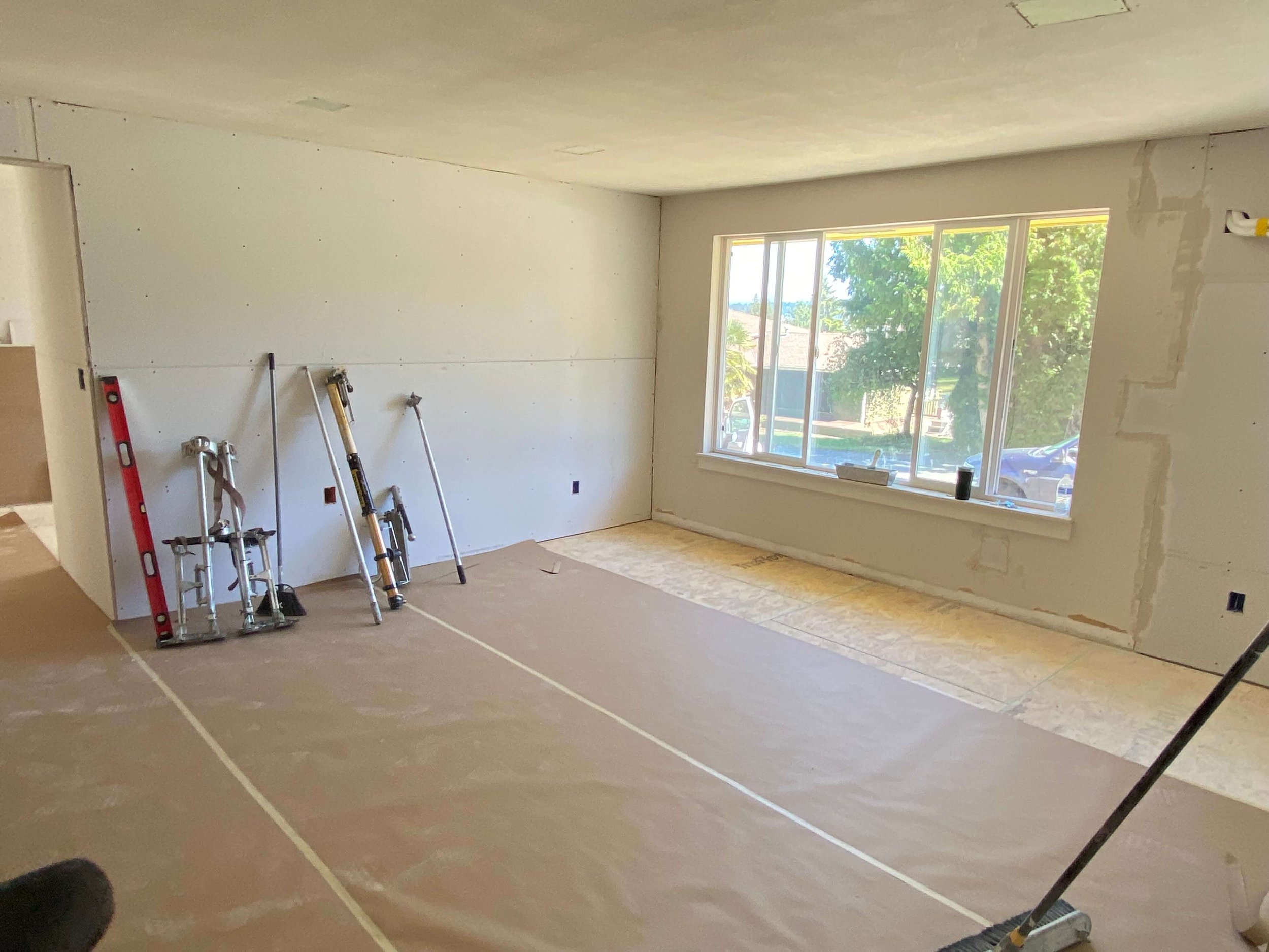 Redmond room prepared for drywall finishing, with protective paper covering the floor and tools staged against the wall.