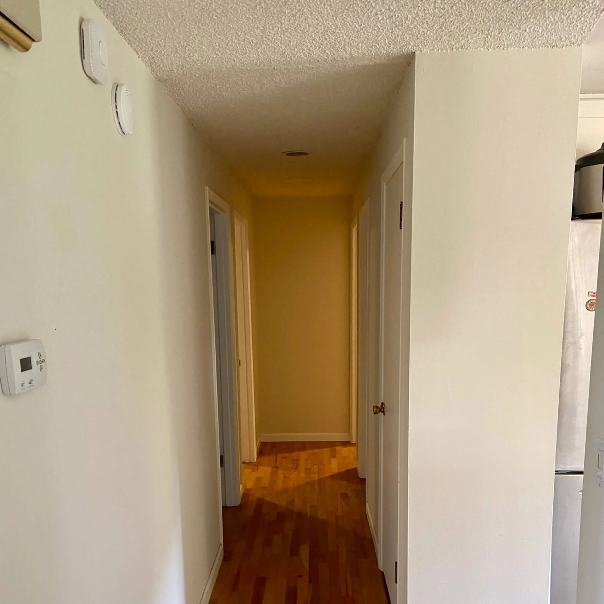 Before popcorn ceiling removal in a Redmond WA hallway showing textured ceiling and walls prior to skim coating and finishing.