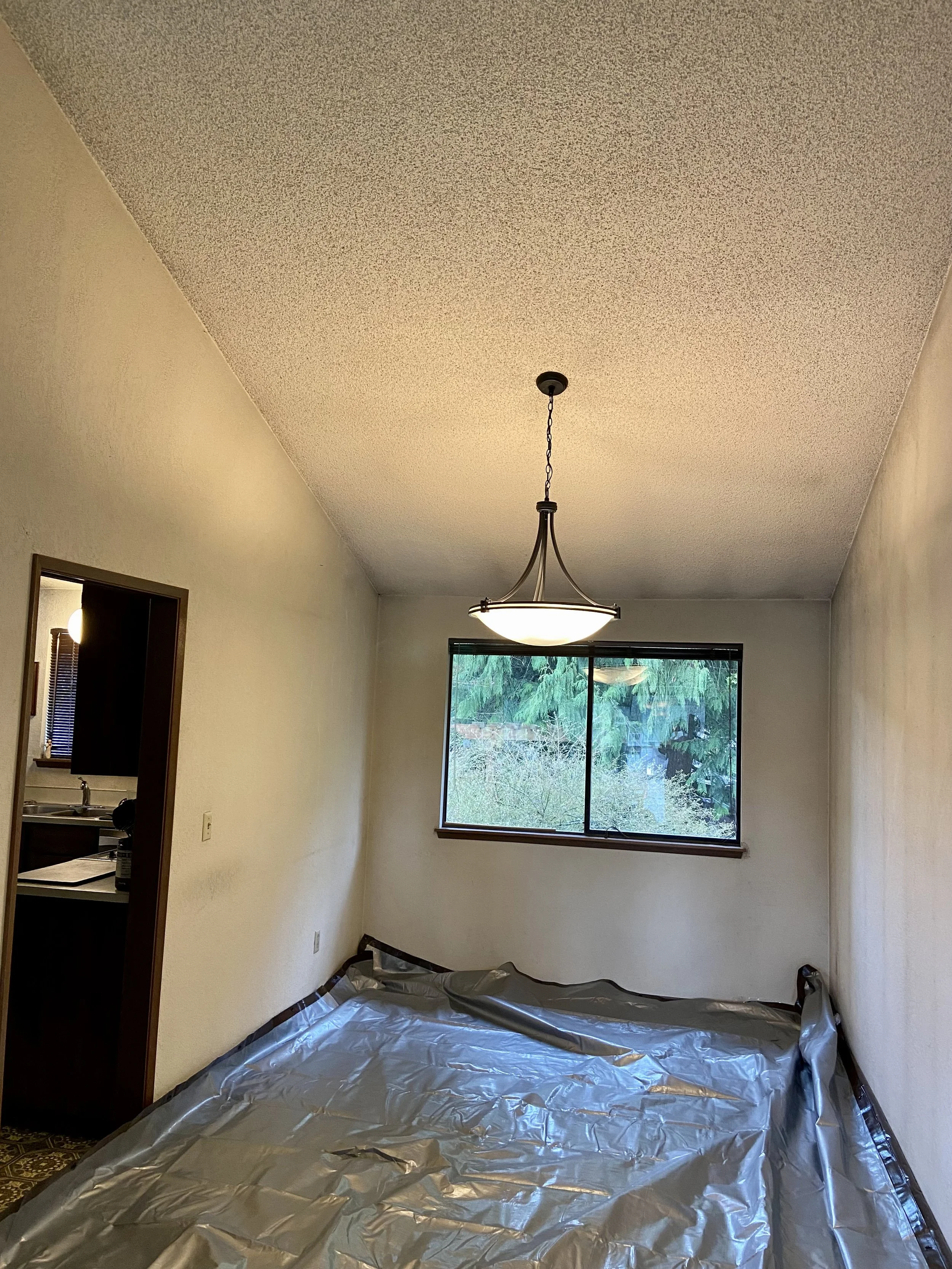 Heavy-duty tarp trapping popcorn ceiling debris during removal in Kirkland, Issaquah, and Bothell homes — L.A. Drywall Inc.