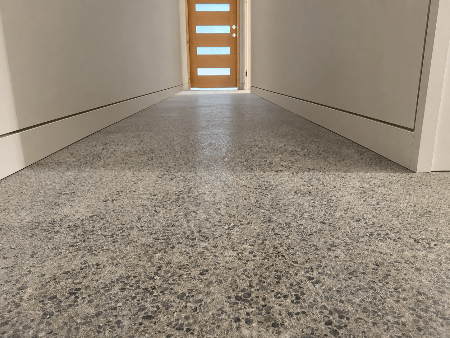 Low-angle view of smooth Level 5 walls with recessed baseboards, a painted ceiling, and polished concrete flooring in a Redmond remodel.