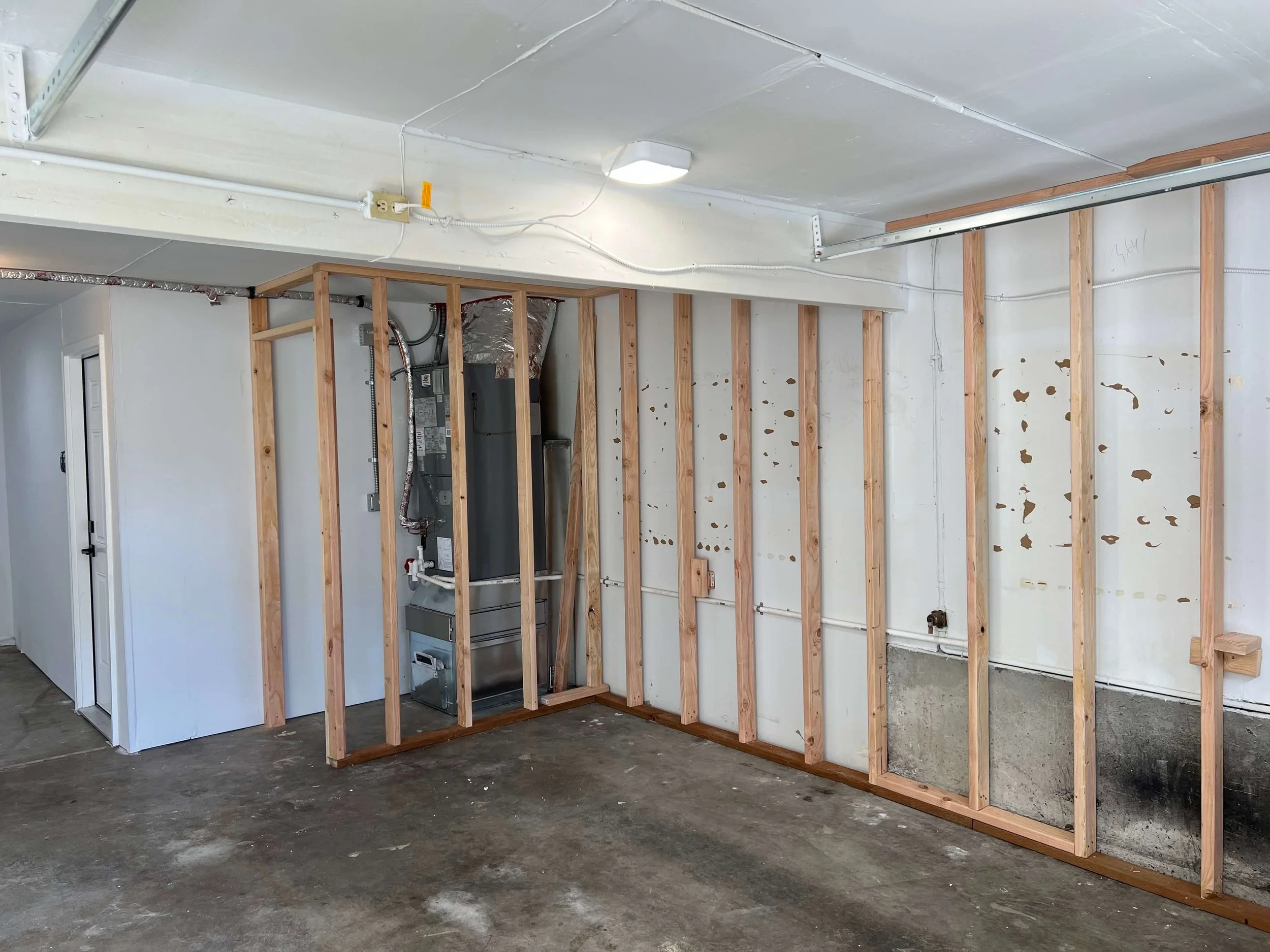 Garage in Kenmore with new wall framing and an equipment enclosure under construction before drywall installation.