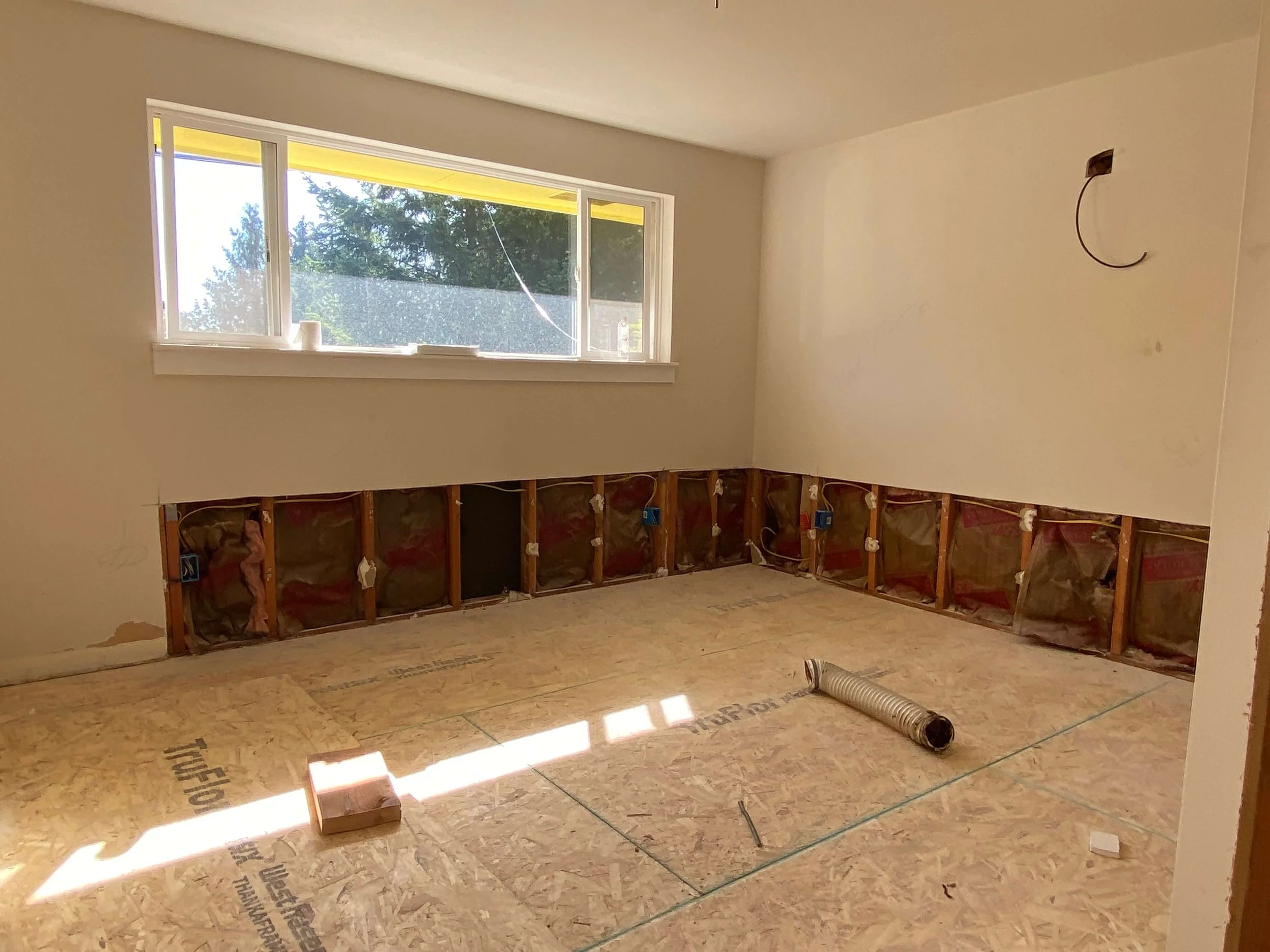 Redmond room with lower drywall removed to expose wall framing and insulation during a whole-home interior remodel.