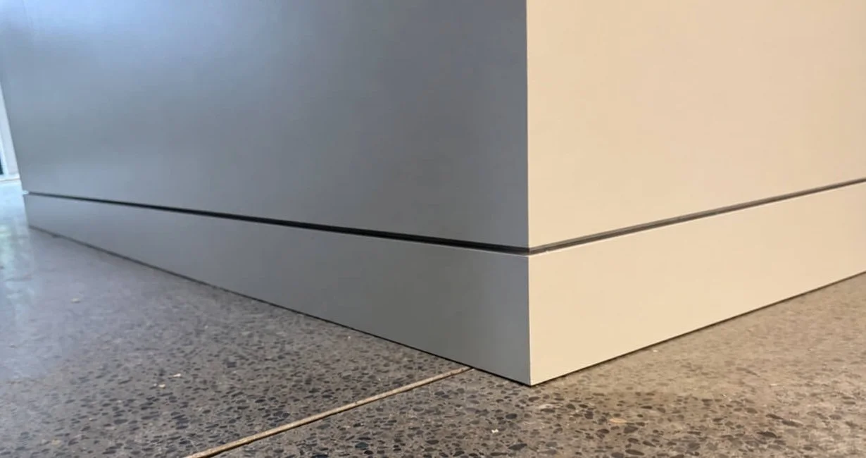 Close-up of a painted drywall corner and recessed baseboard shadow reveal in Redmond, WA.