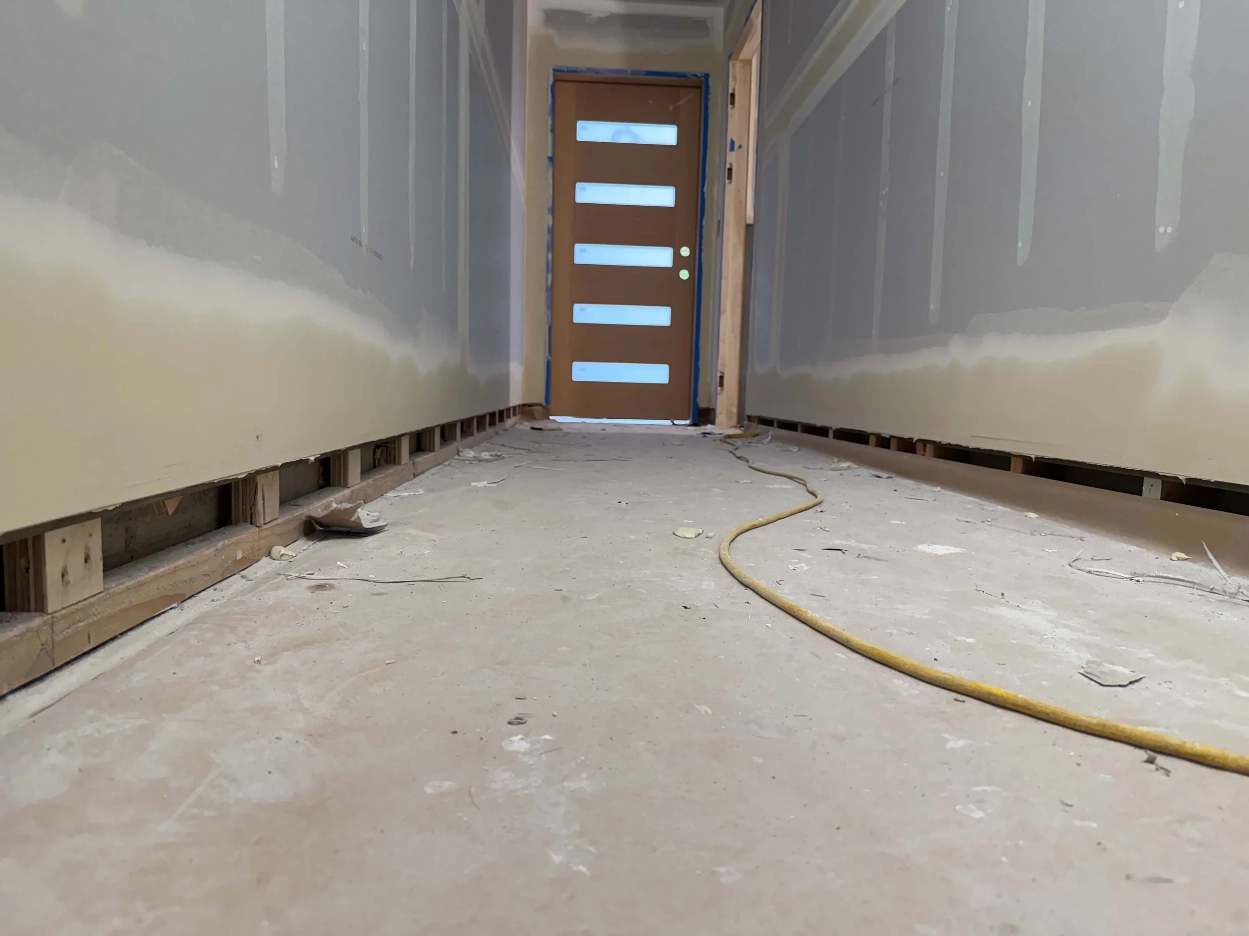 Redmond hallway during recessed baseboard preparation before the lower drywall was completed.