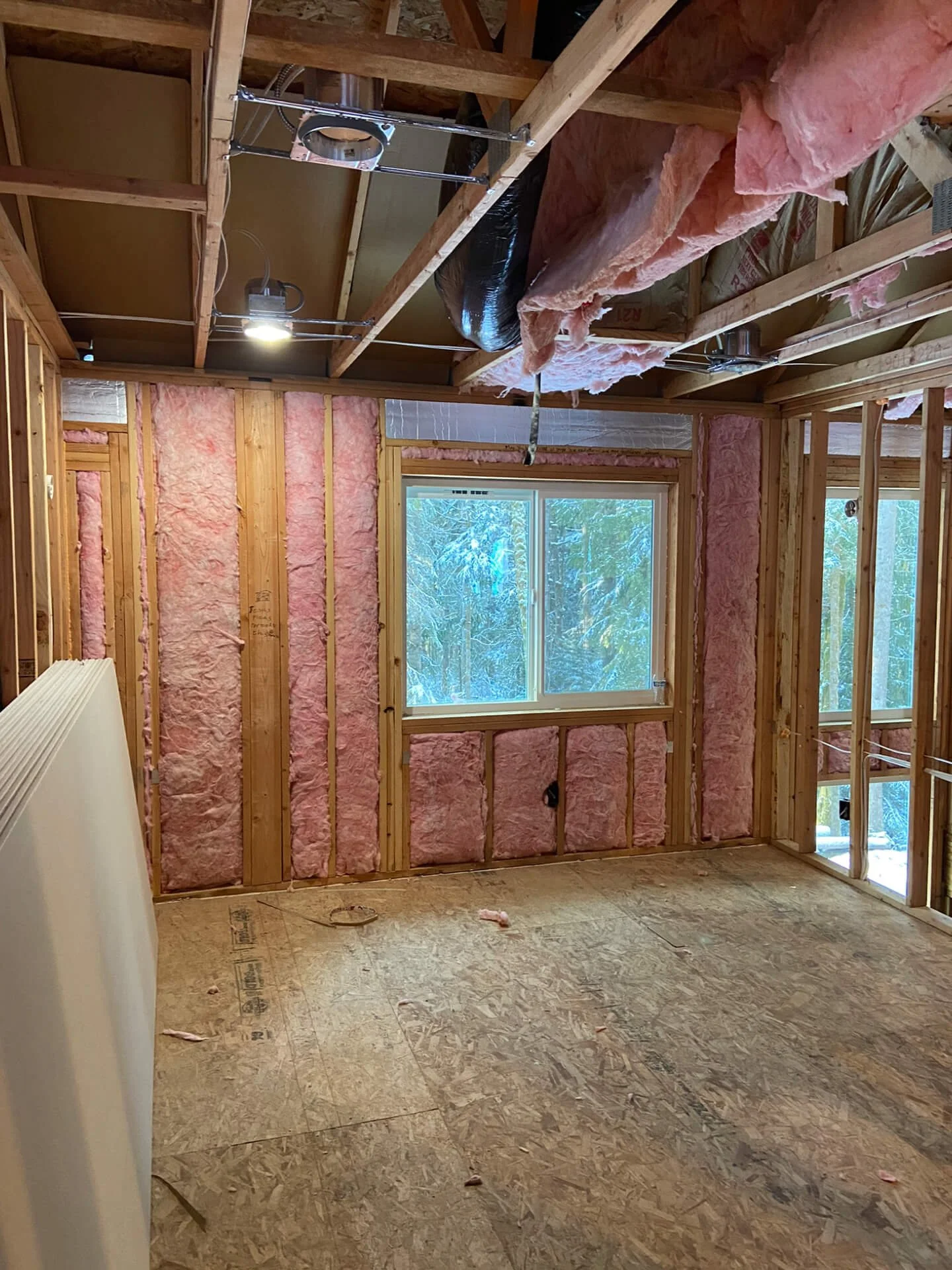 Before drywall installation in an Issaquah ADU with exposed framing, insulation, and a large window.