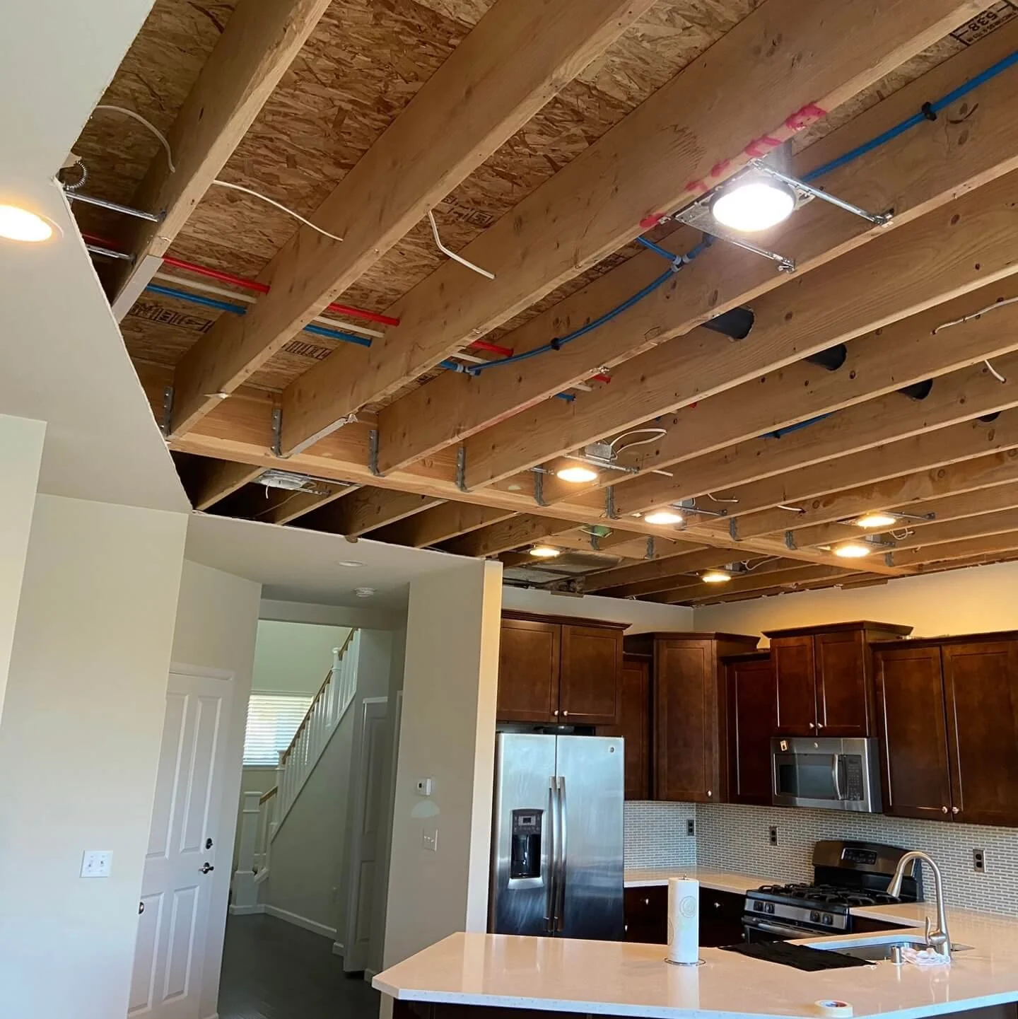 Before water damage restoration in Lynnwood WA showing ceiling drywall removed due to moisture exposure, with framing, electrical, and plumbing exposed.