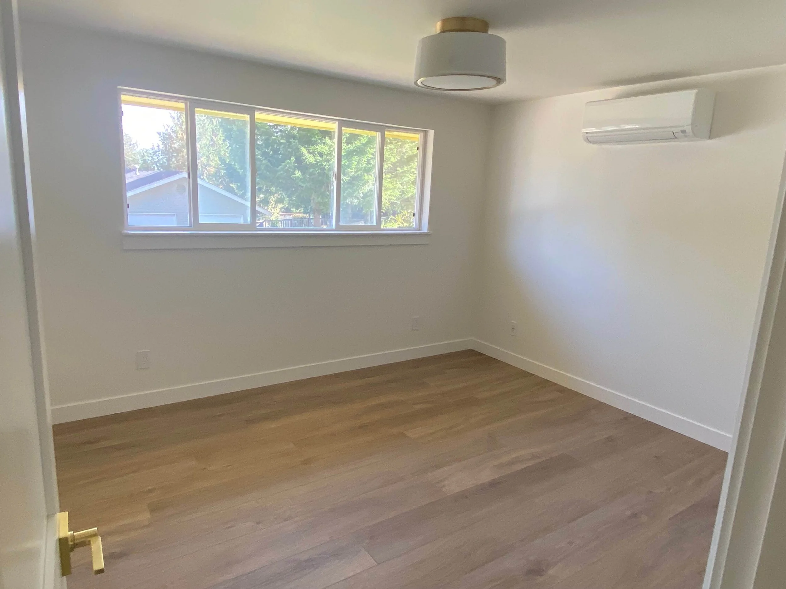 Completed Redmond remodel with smooth painted walls, finished flooring and a wall-mounted heating and cooling unit.