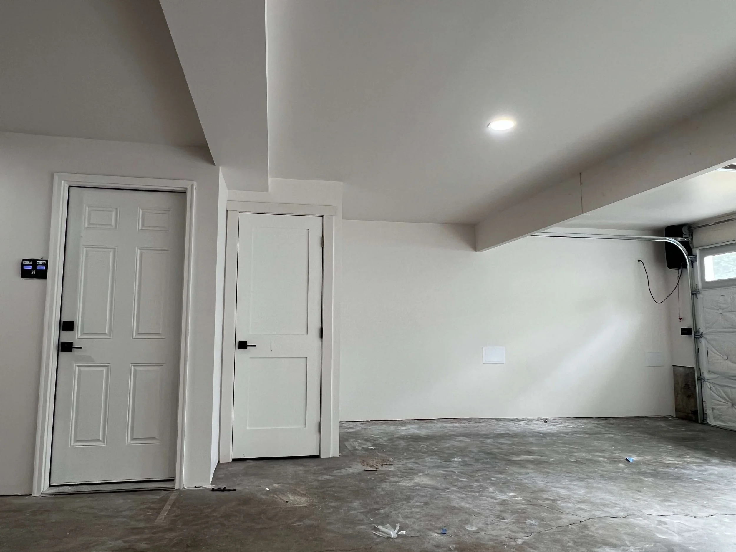 Completed Kenmore garage with enclosed framing and mechanical areas, Level 4 drywall, PVA primer, and white interior paint.