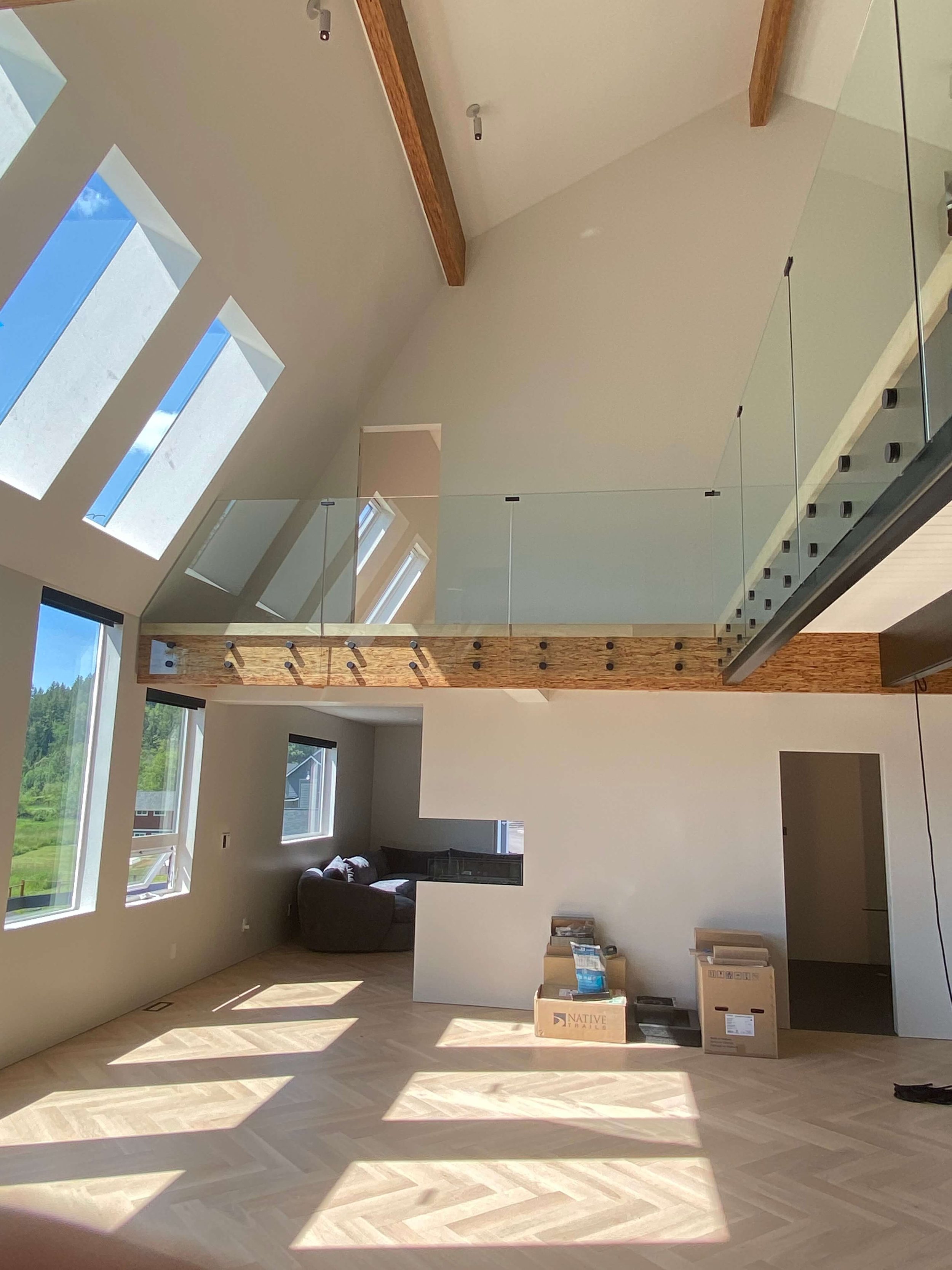 Smooth Level 5 drywall walls and vaulted ceiling around skylights and an upper-level glass railing.