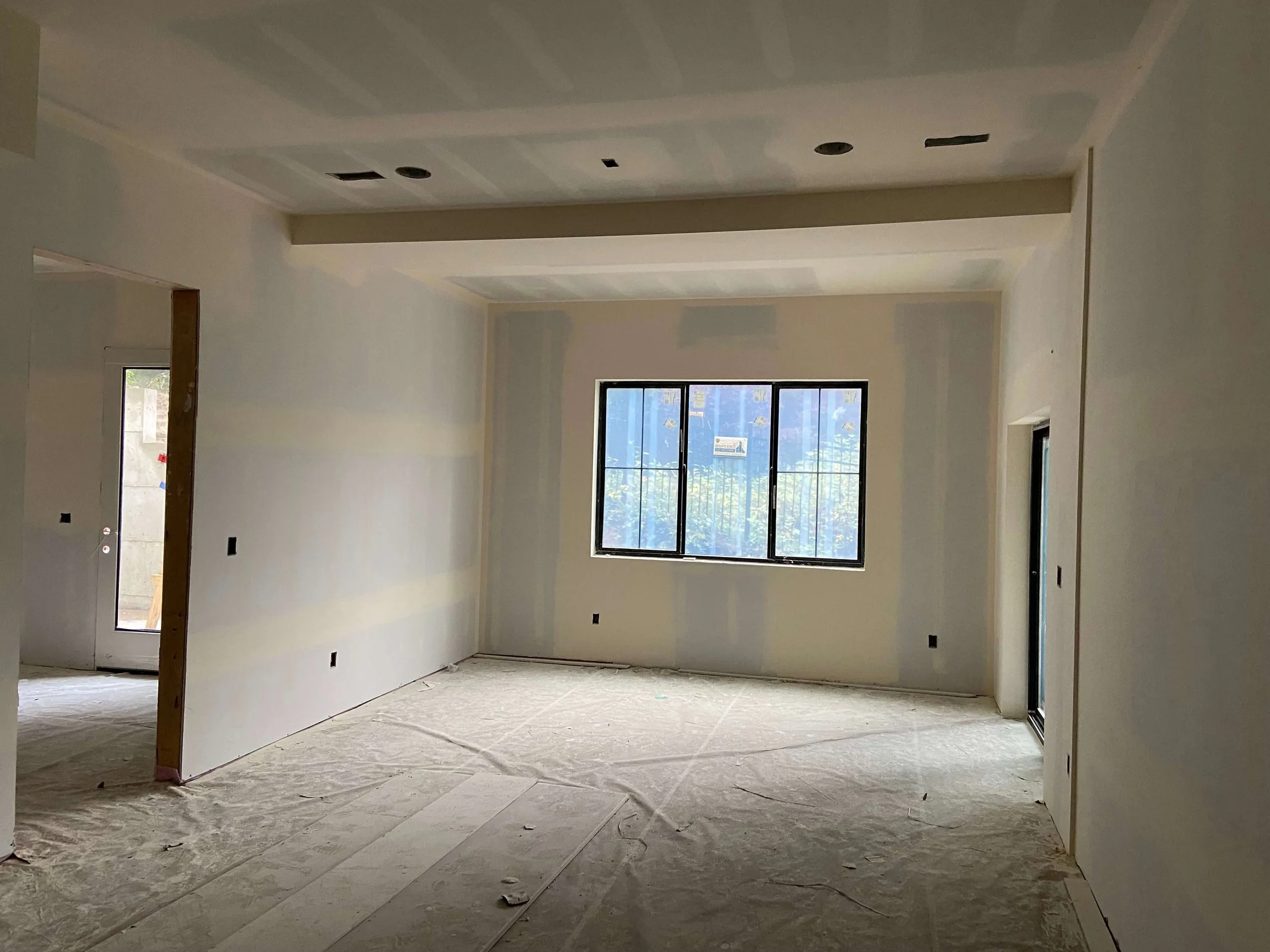 Snohomish interior during drywall finishing with visible taped joints, recessed-light openings, and large windows.