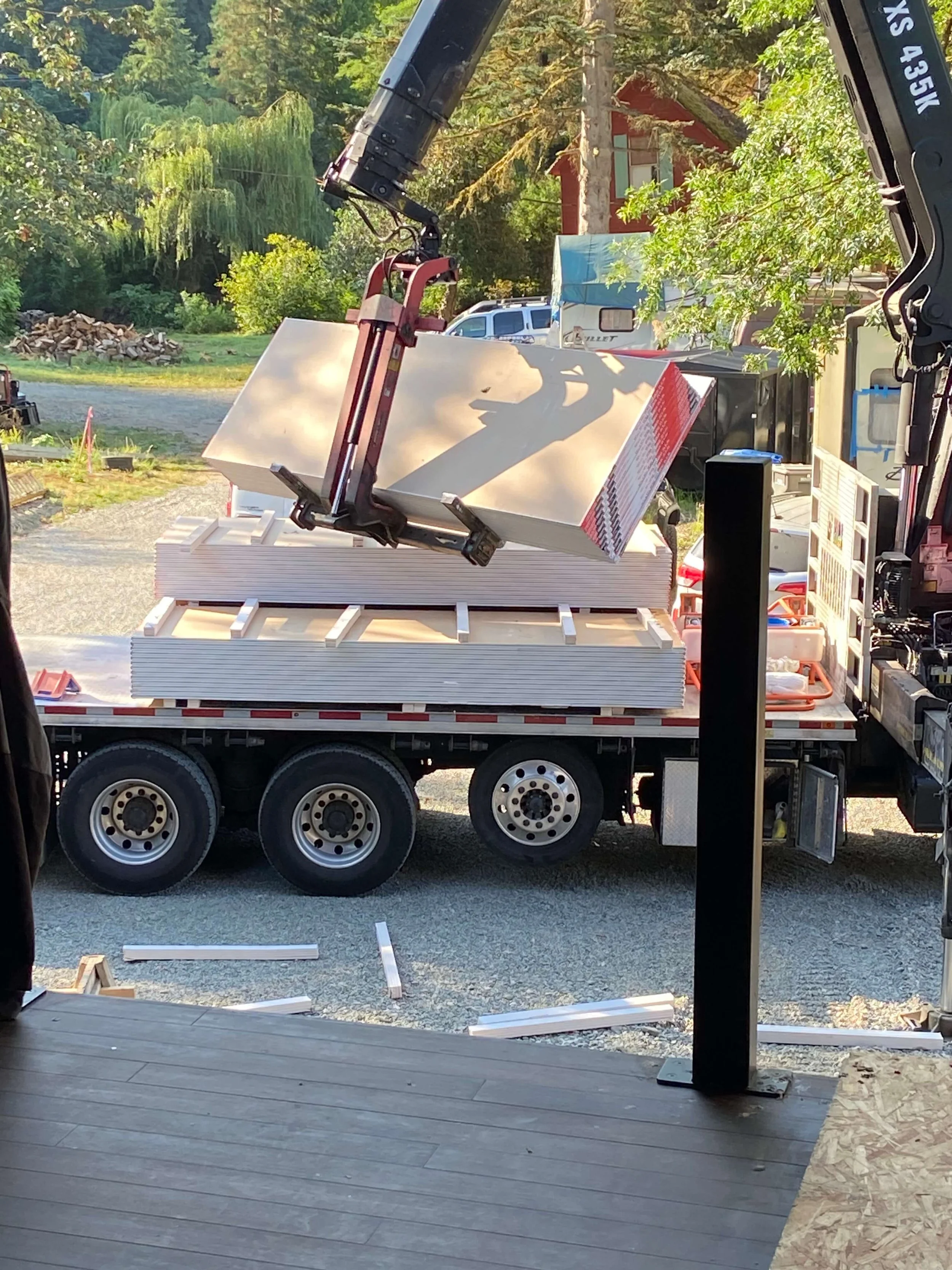Drywall sheets being unloaded from a delivery truck for strategic material stocking at a residential project.