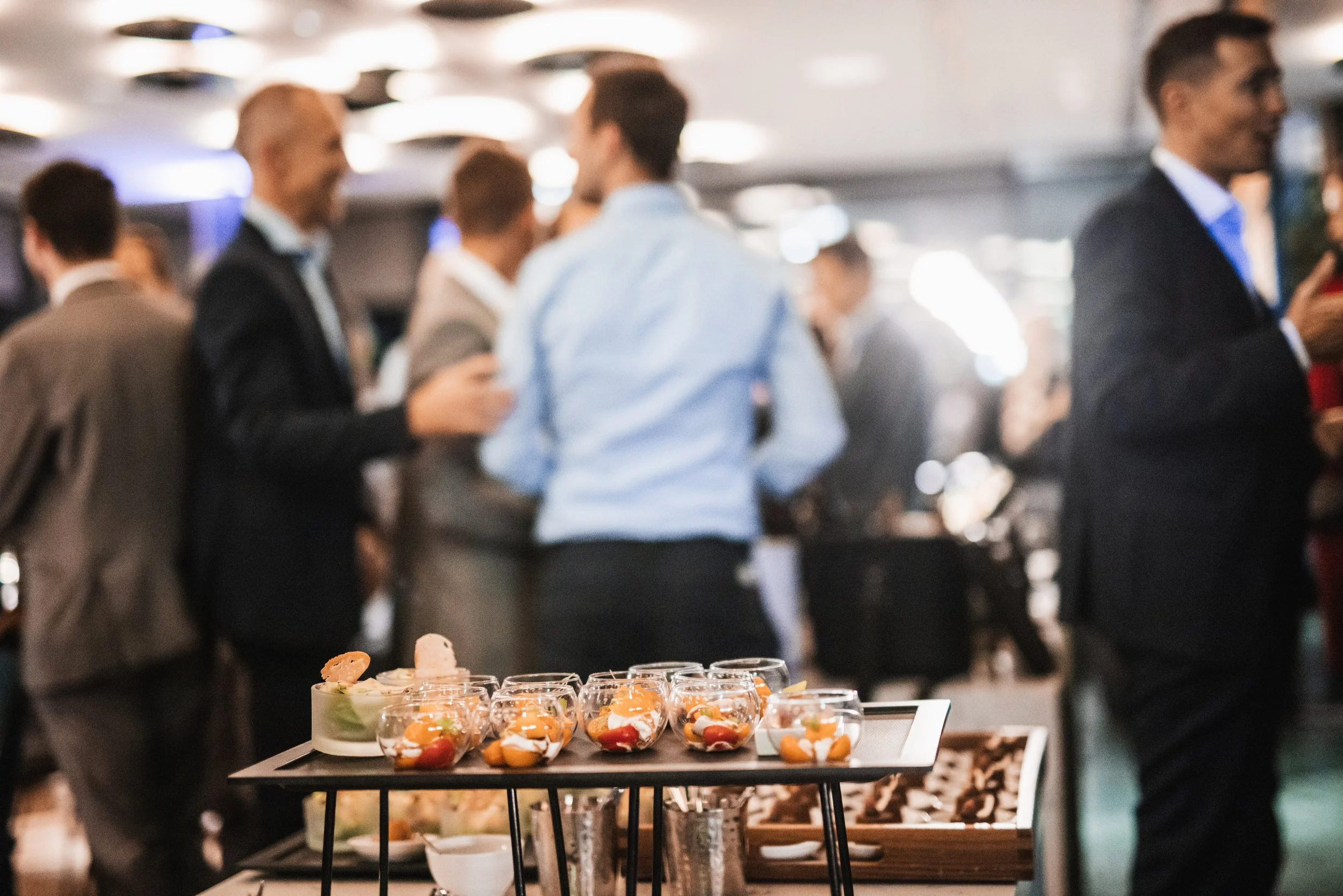 Appetizers on a tray with people socializing in the background at a formal event.