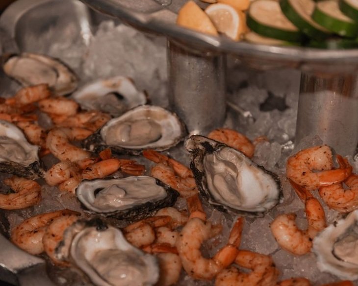 Seafood platter with oysters on the half shell and cooked shrimp on ice.