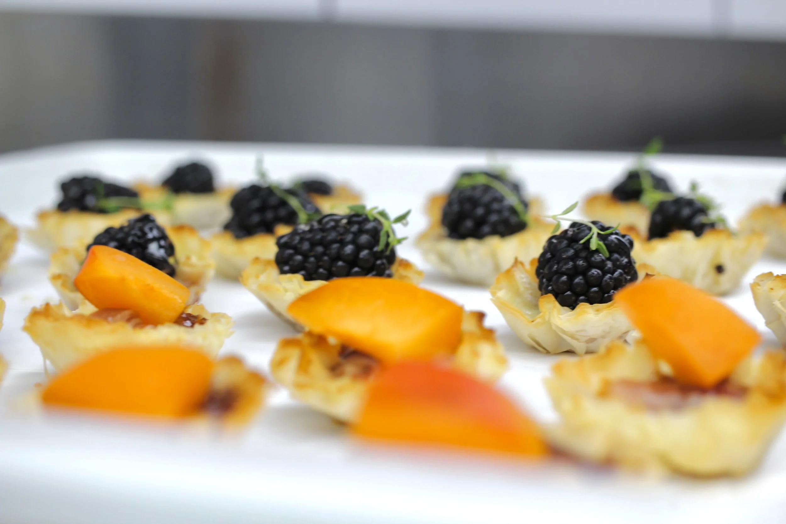Plate of assorted mini tartlets topped with blackberries and small green garnishes, with some tartlets featuring apricot slices at The Bellview.