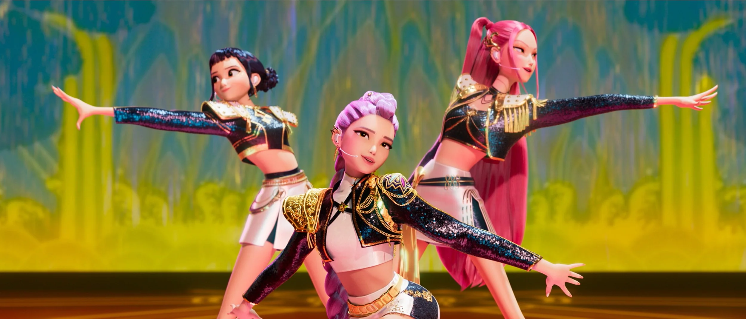 A red-haired woman with blue eyes and freckles, smiling at the camera, sitting on the ground in front of a light gray brick wall, wearing a black jacket over a colorful striped top and brown pants.