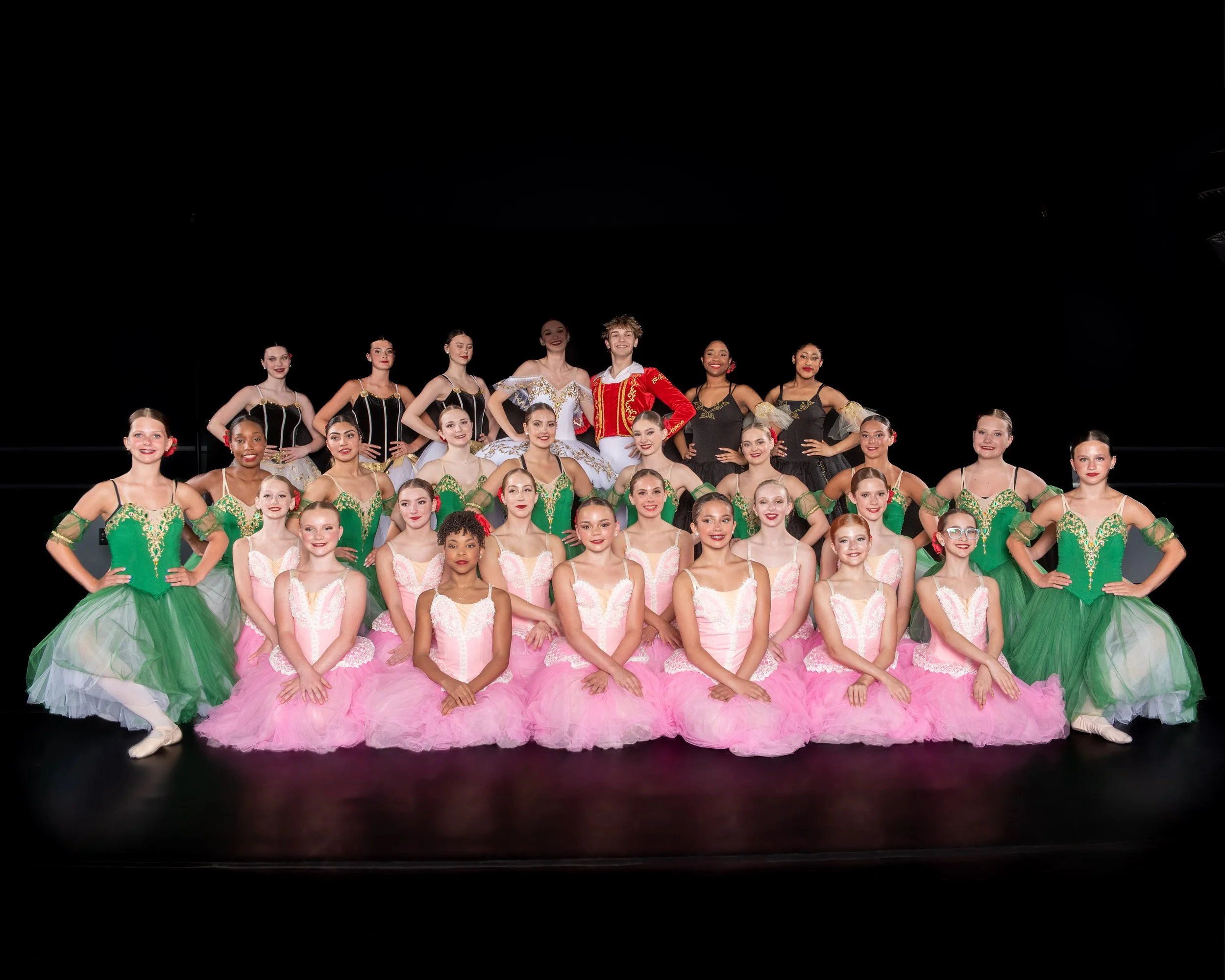 Group of ballet dancers in colorful costumes posing on stage.