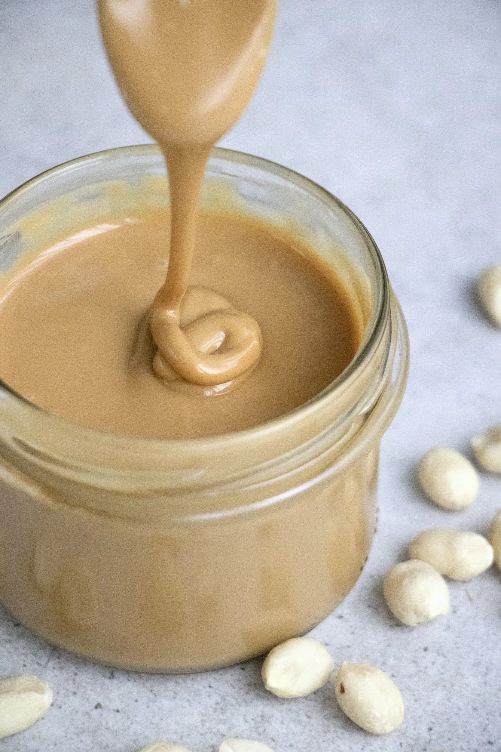 Soft peanut butter running into a jar.