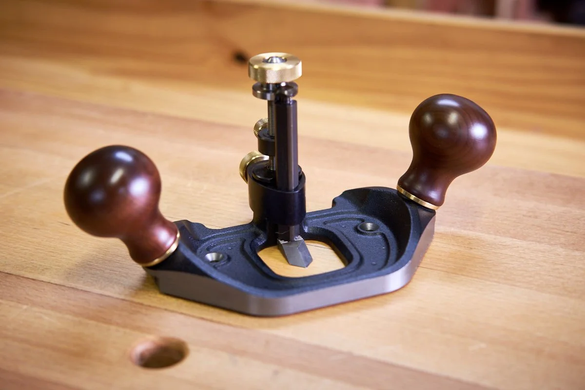 Plan view of a Veritas router hand plane, based on the Stanley 71 on top of a wooden workbench top.