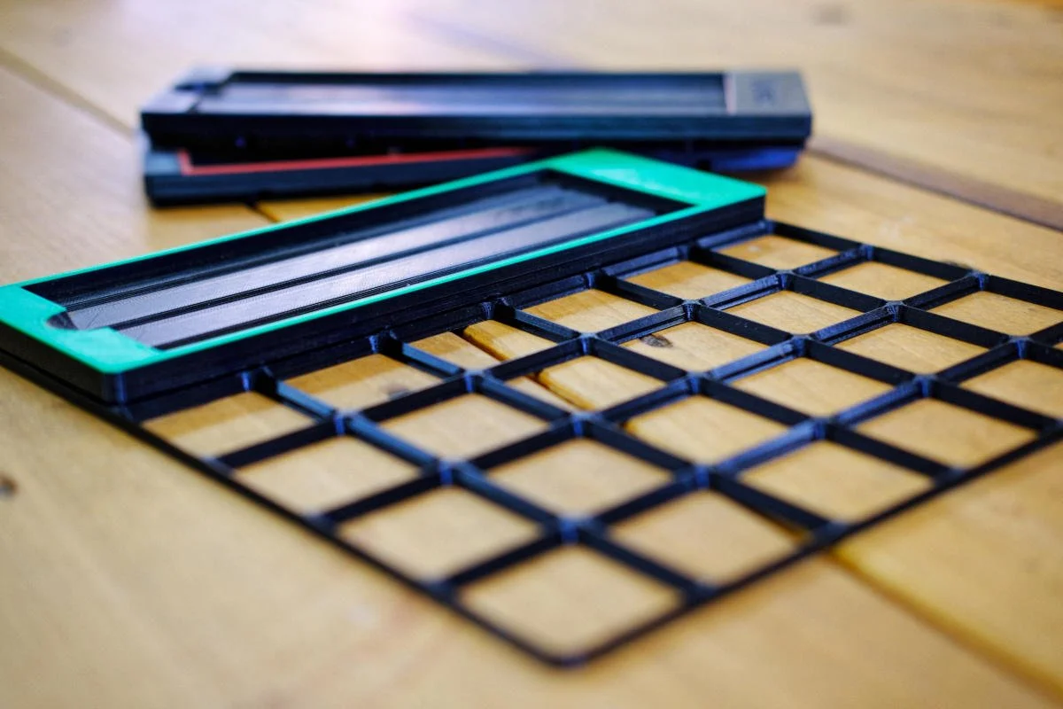 Gridfinity based, PETG 3D printed, diamond sharpening stone holder prototypes set on a Gridfinity base plate on a wood working workbench top.