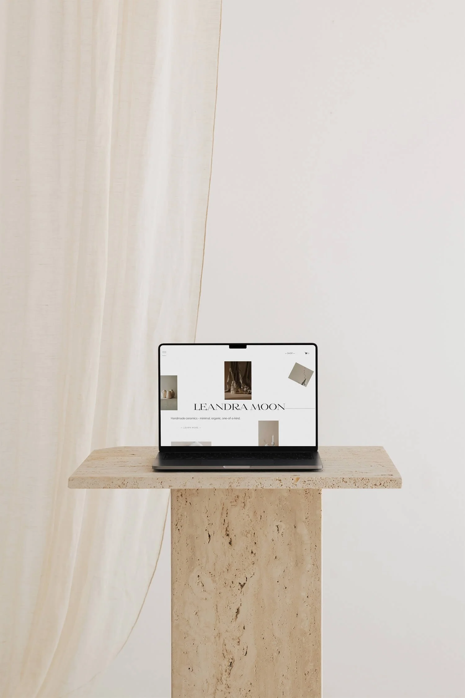 Laptop sitting on a stone pedestal in front of a breezy white curtain, displaying Rebecca Giger Studio's base design, Leandra Moon