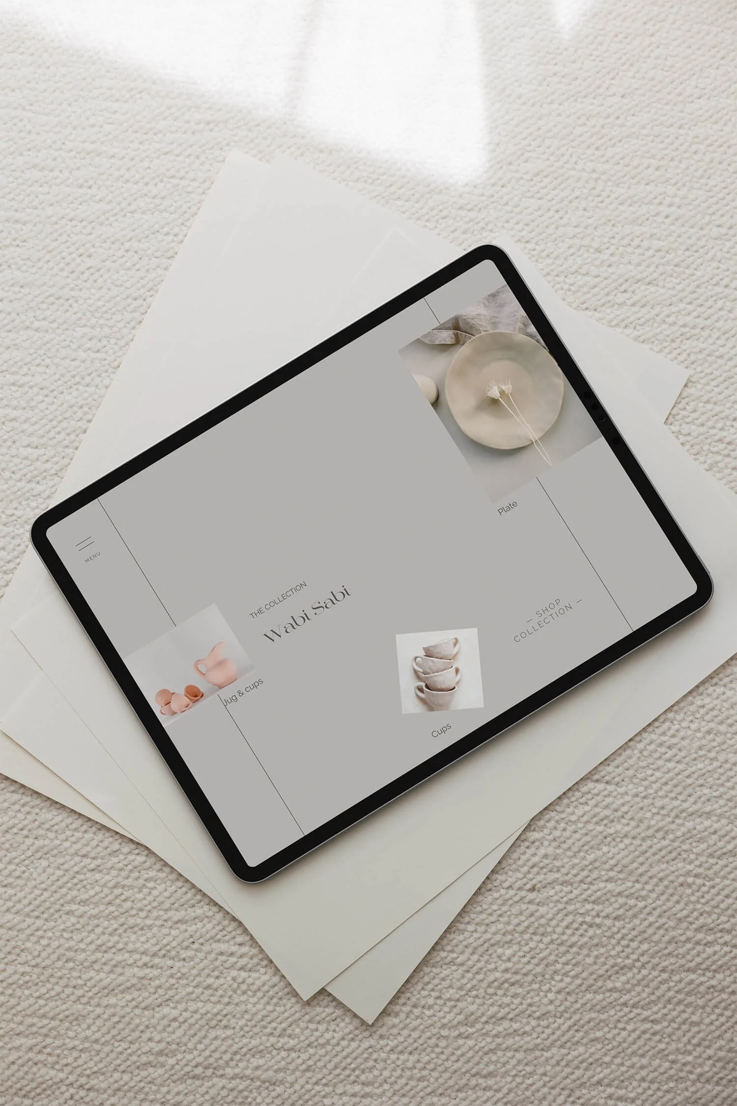ipad laying on a stack of papers, displaying the one-week ecommerce package base design, Leandra Moon