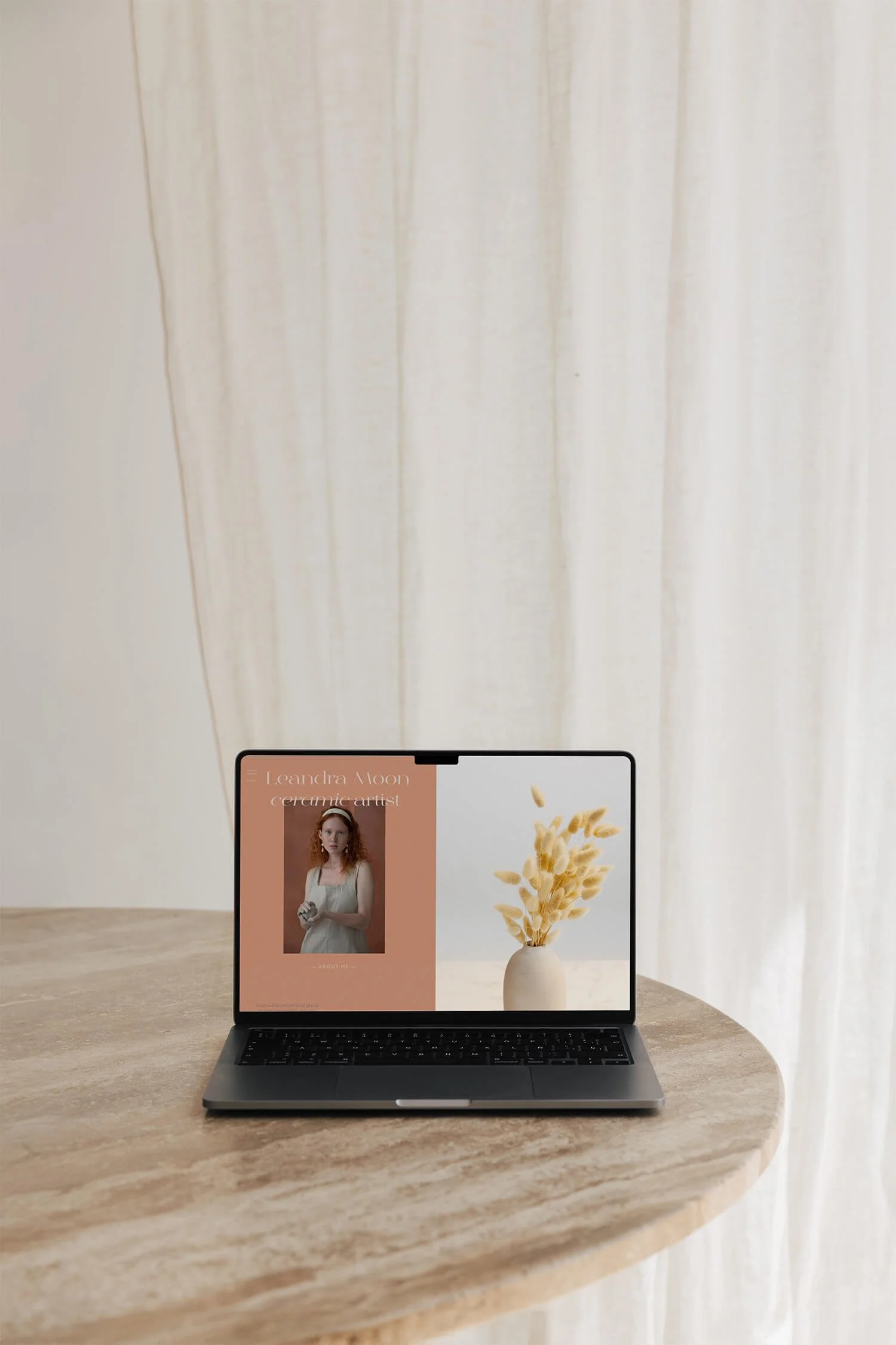 Open laptop on a stone table displaying an elegant website for a small ceramics business, against a light background.
