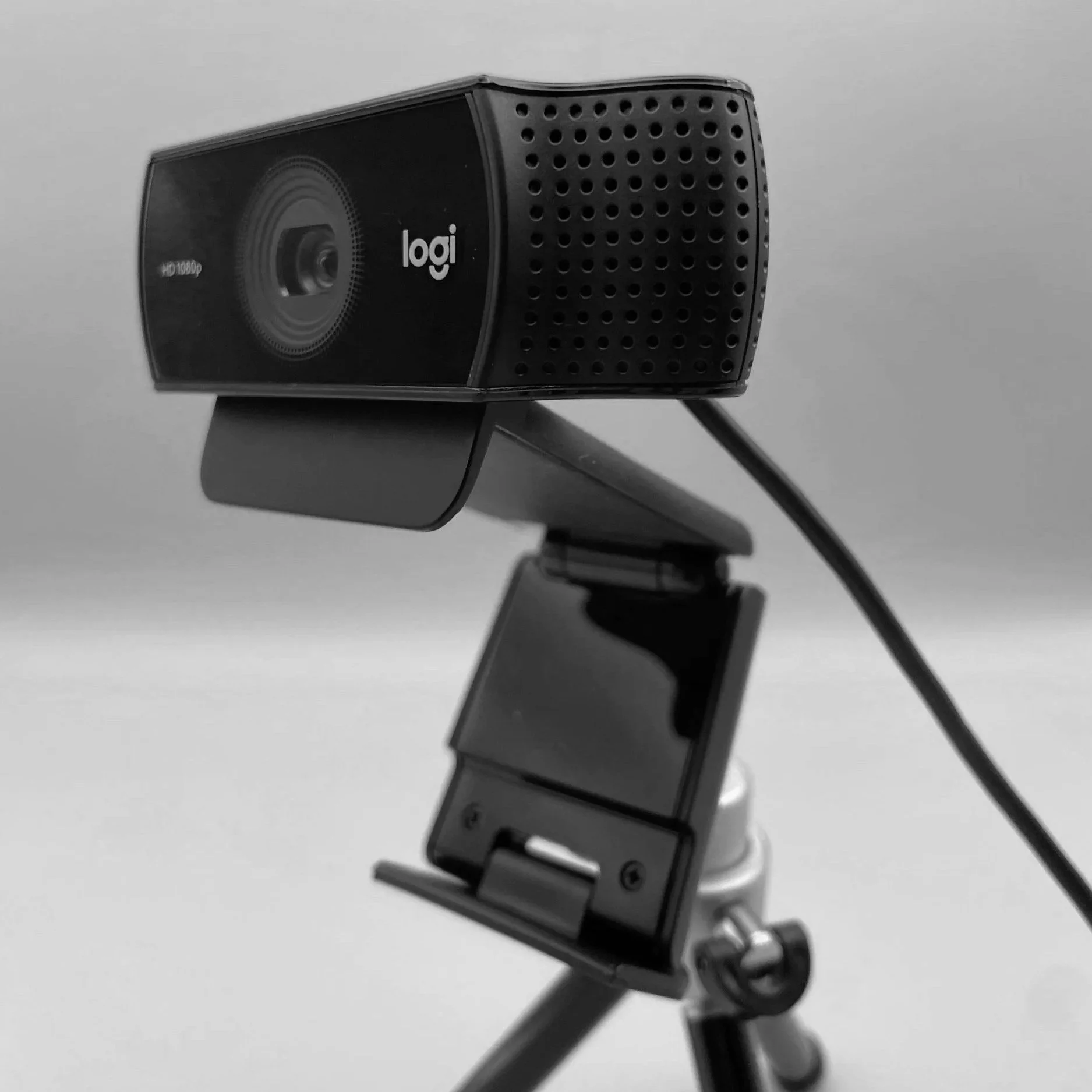 Black and gray Logitech webcam mounted on an adjustable arm against a plain background.