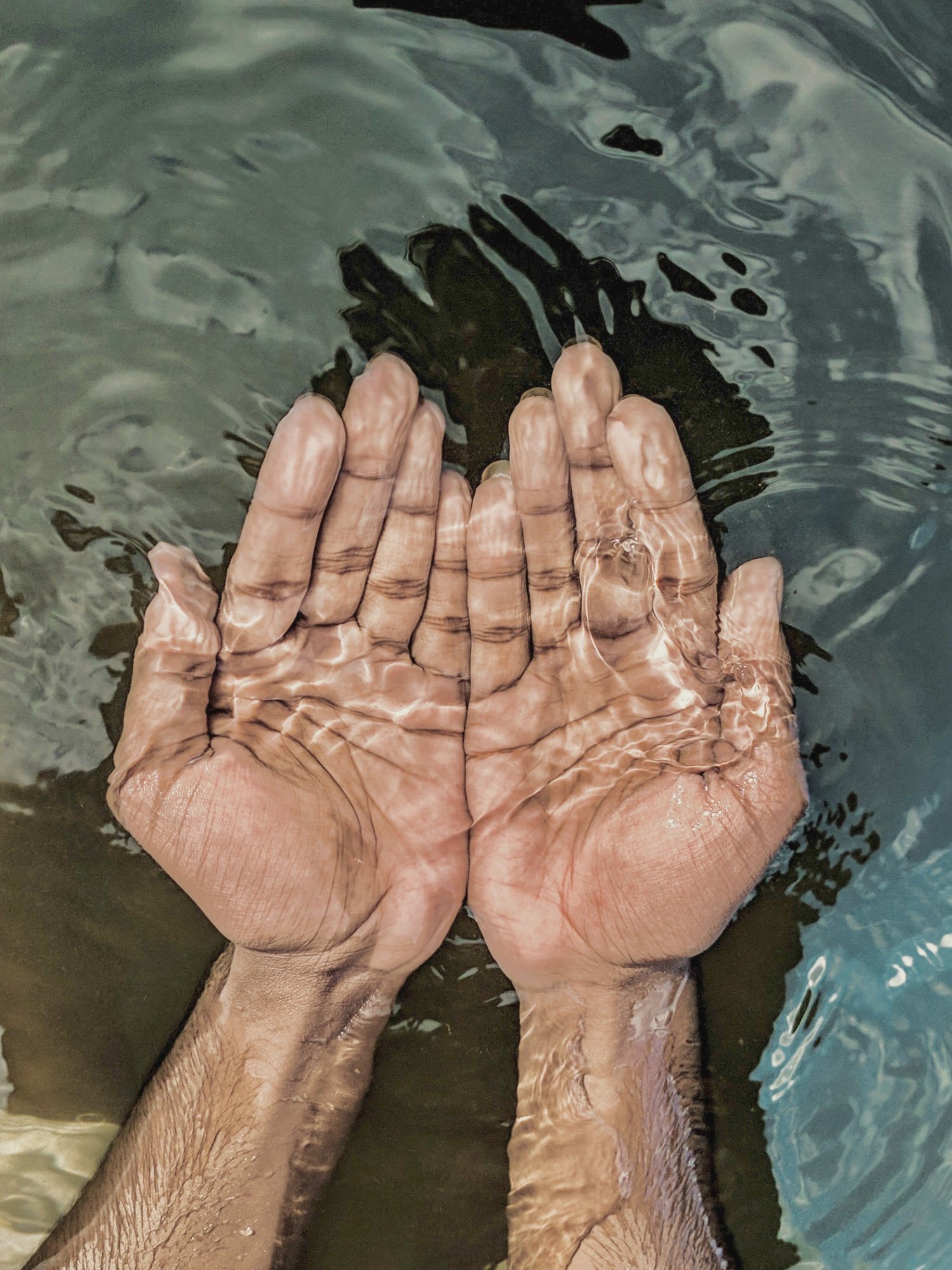 man scooping up water with hands