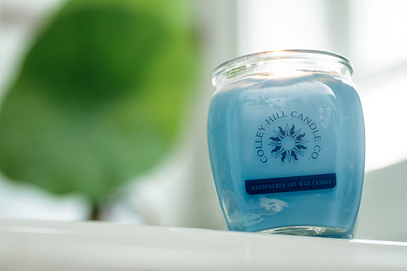 Blue soy wax candle in a glass jar with a lid, labeled 'Colley Hill Candle Co., Handpoured Soy Wax Candle'.
