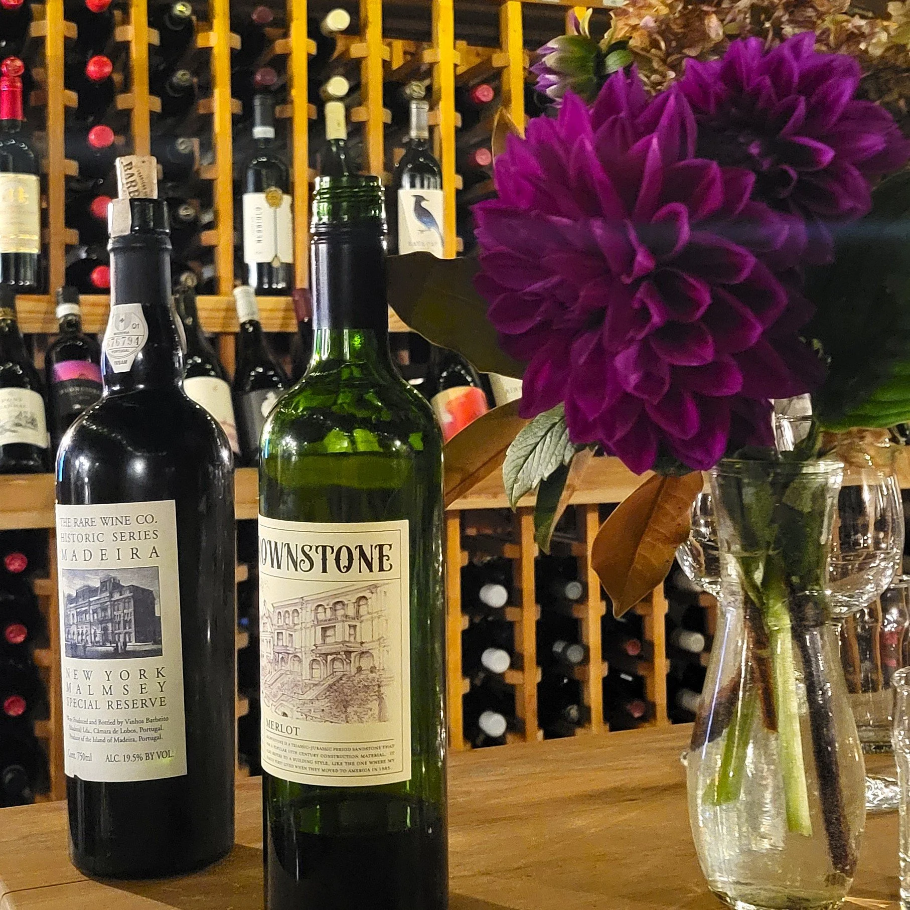 Wine racks line the walls and tasting bottles sit on a table