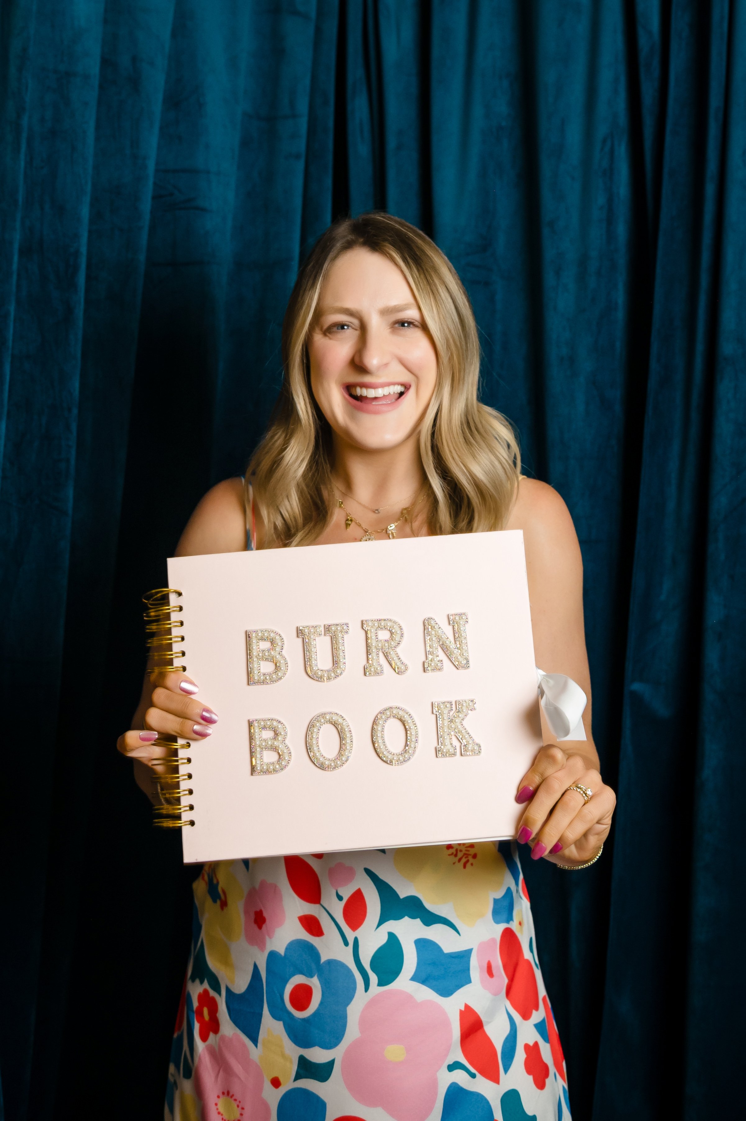 Therapist holding a pink 'Burn Book' journal, symbolizing letting go of negative self-talk and silencing the inner mean girl