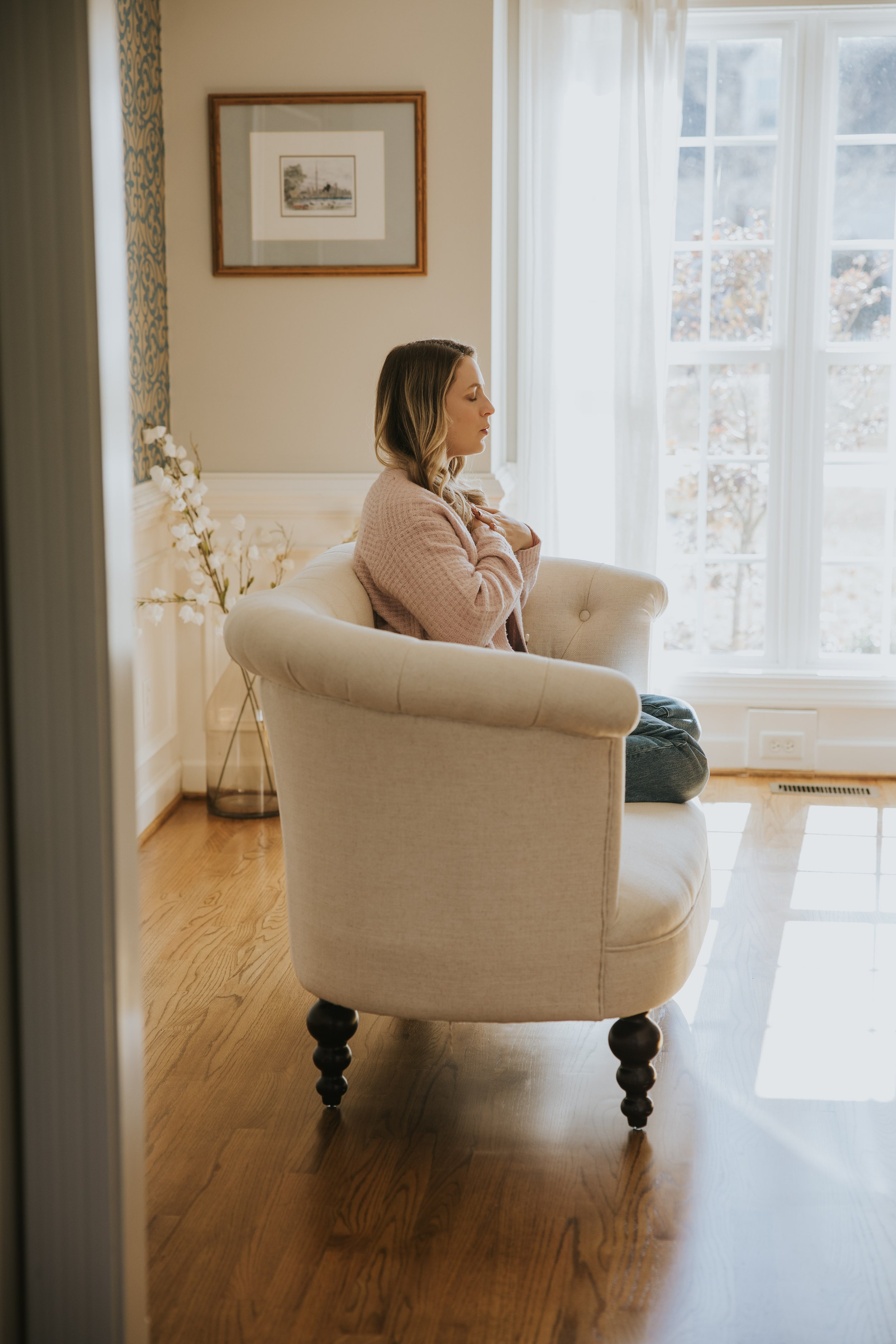 Woman sitting quietly by a window, taking a reflective moment alone