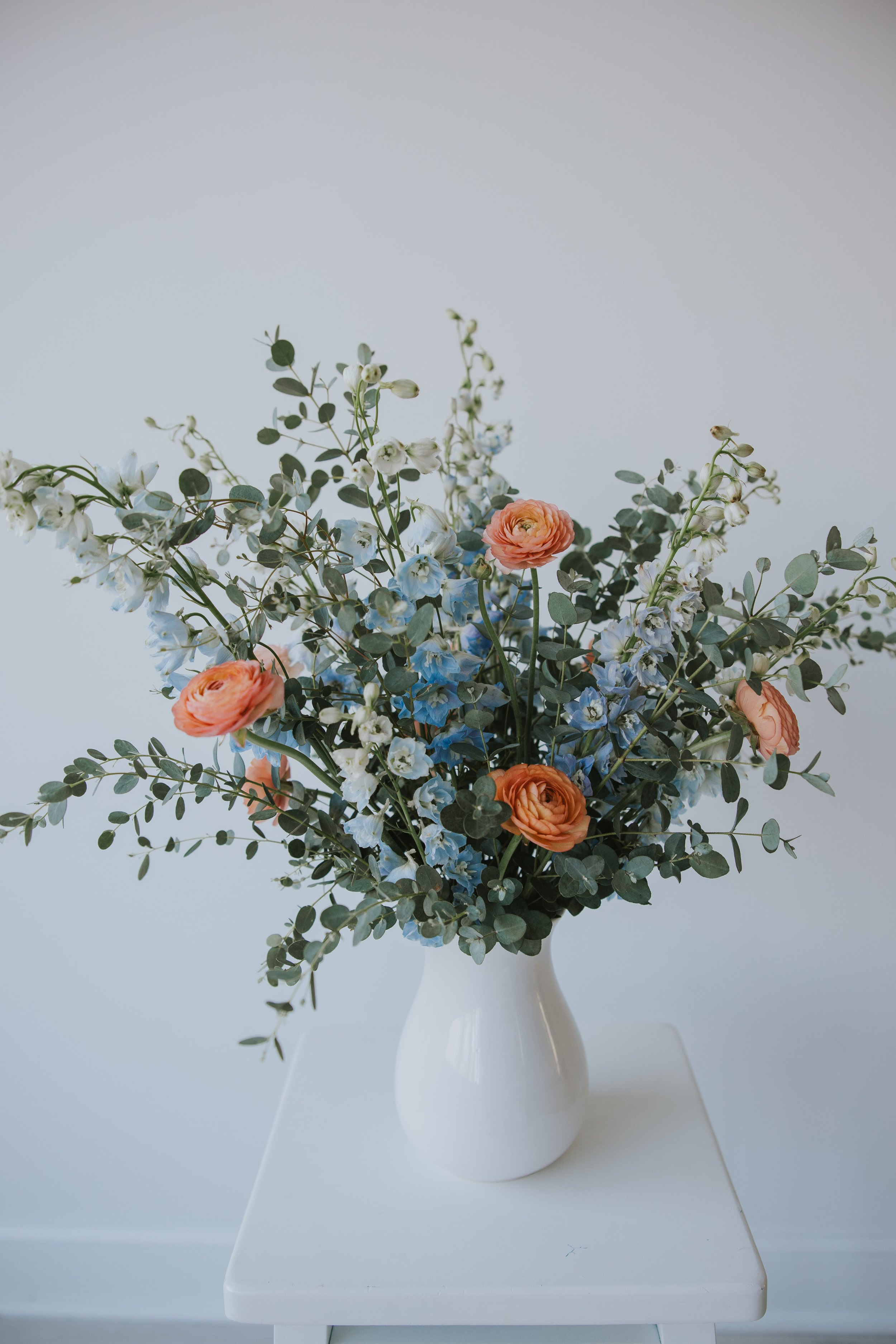 Vase of orange and blue ranunculus and delphinium flowers