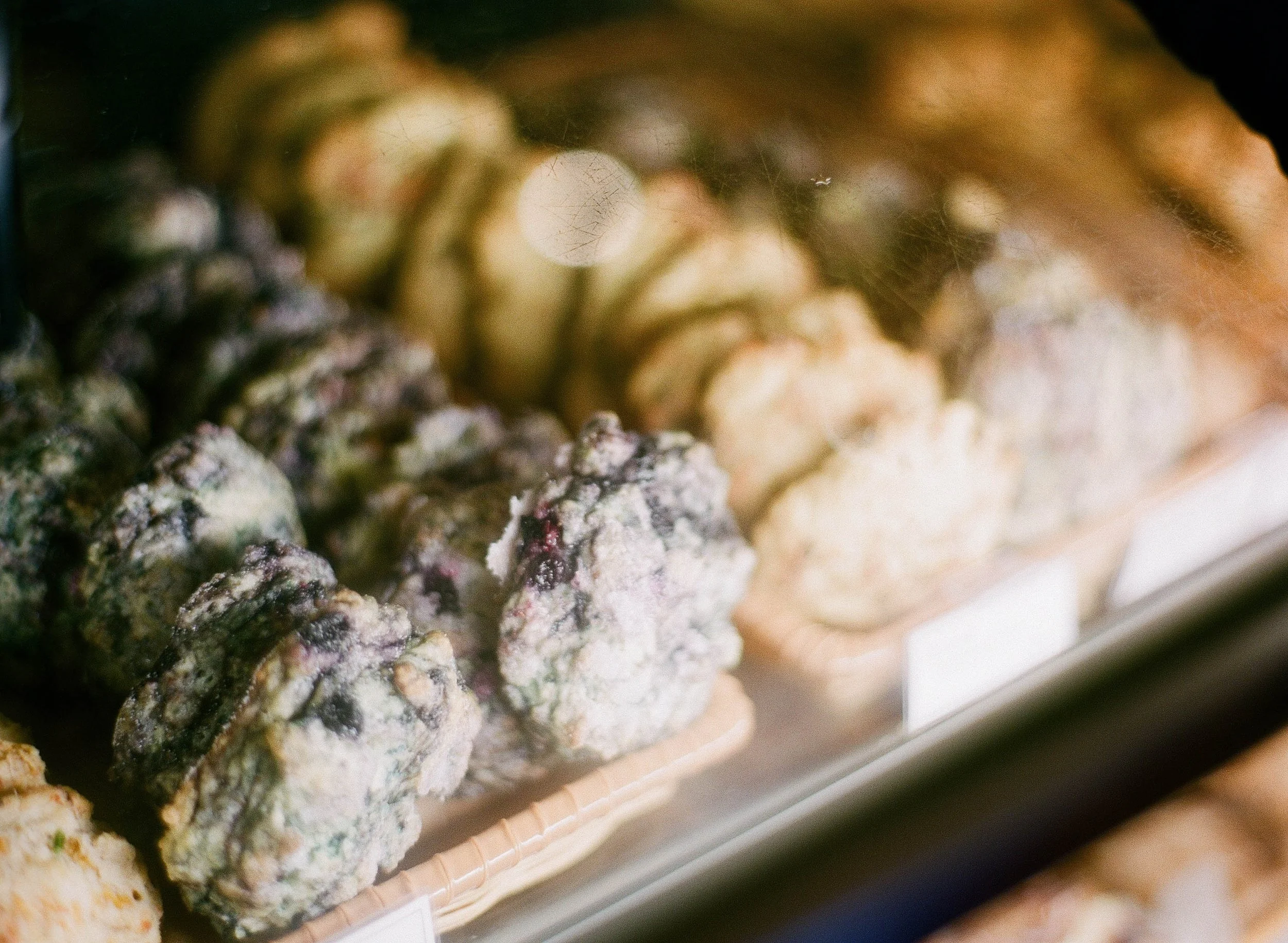 Display of various baked scones in a bakery showcase.