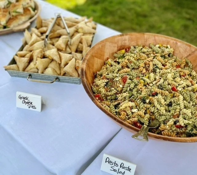 tray of Greek cheese pies and bowl of pesto pasta salad