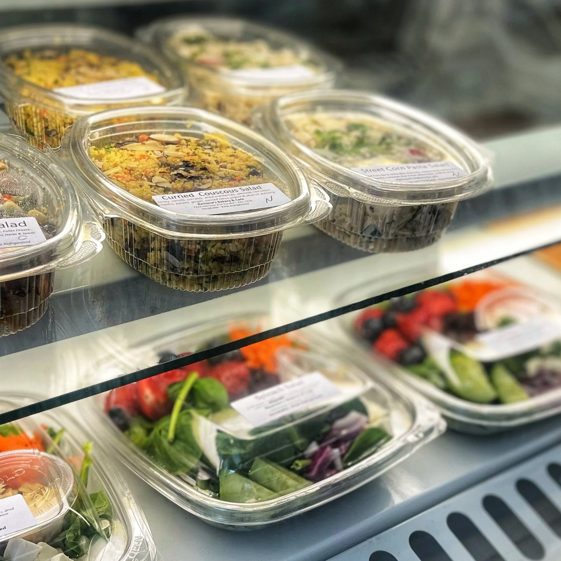various grab and go salads in plastic containers displayed in cold case