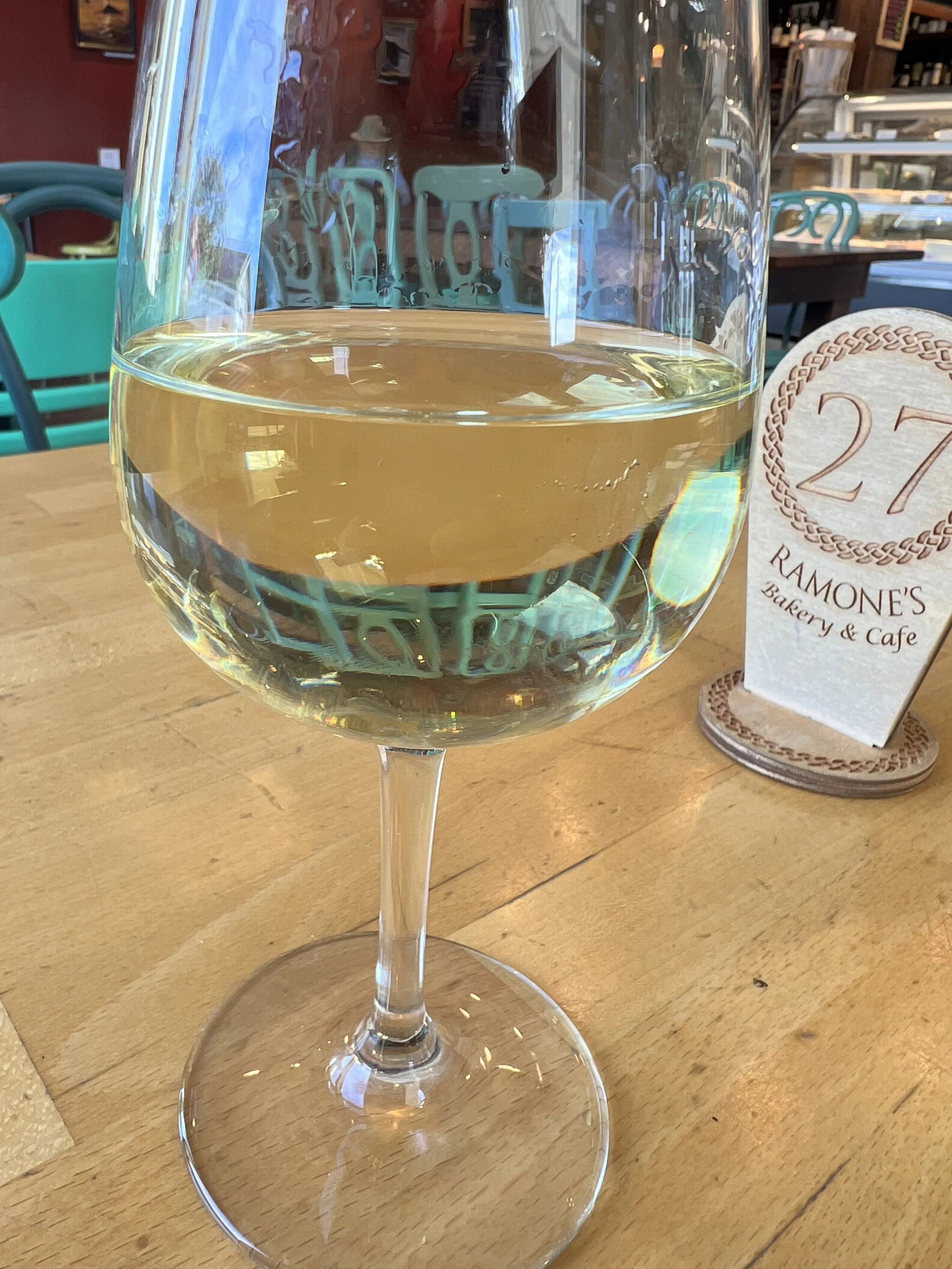 glass of white wine with cafe in background