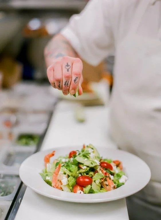 Cook squeezing lime over green salad with prawns
