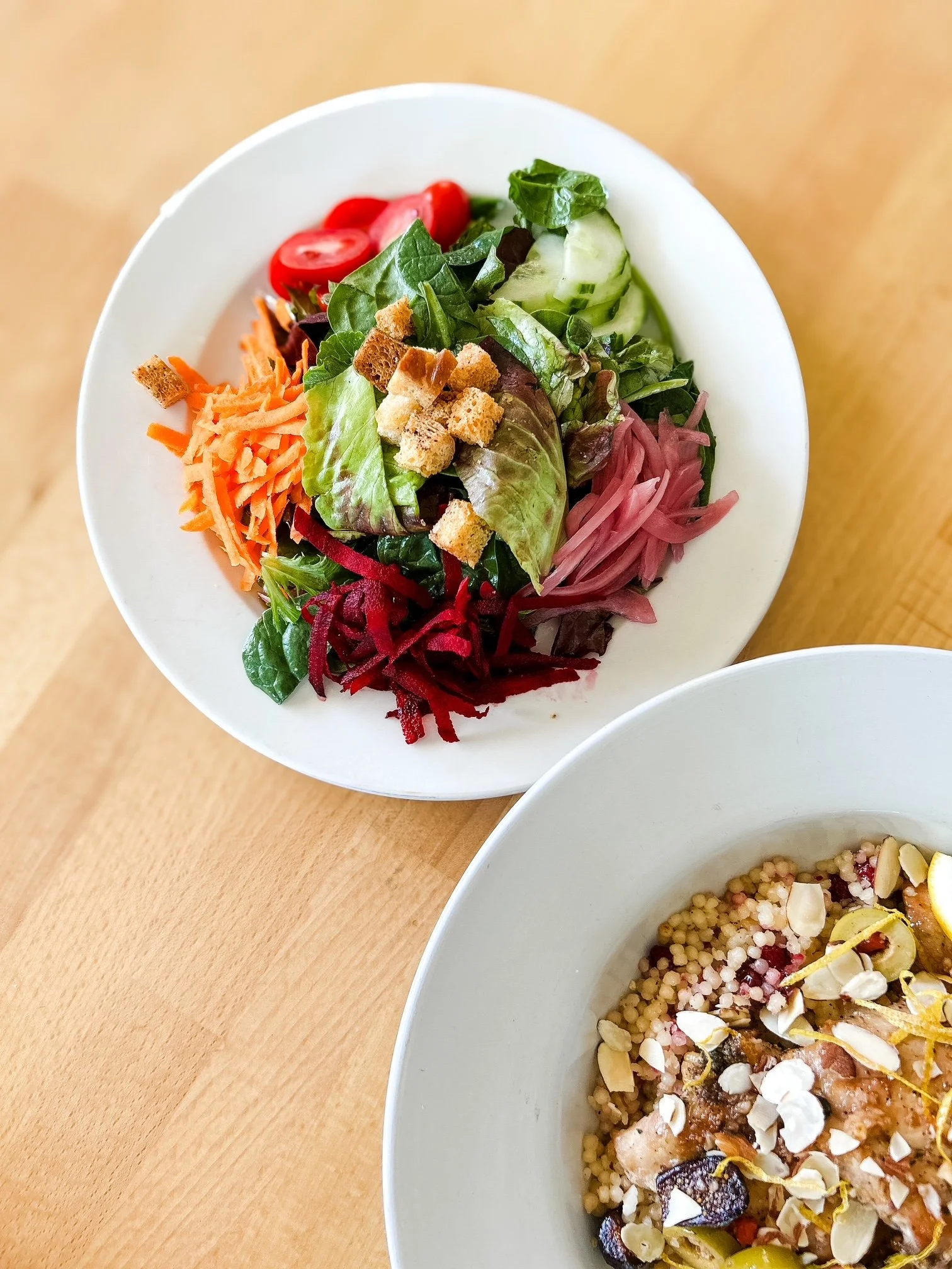 colorful house salad next to cous cous chicken dish