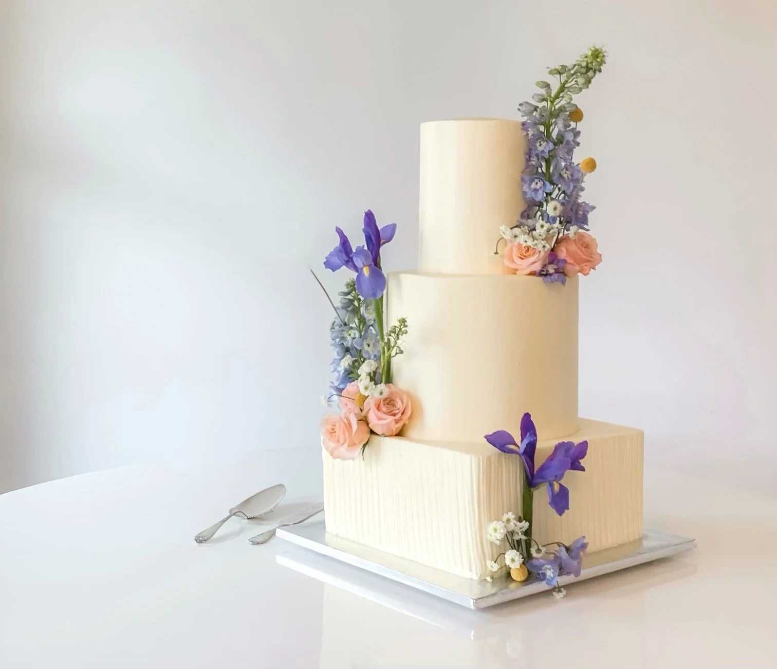 three-tiered vanilla buttercream cake with square and round tiers