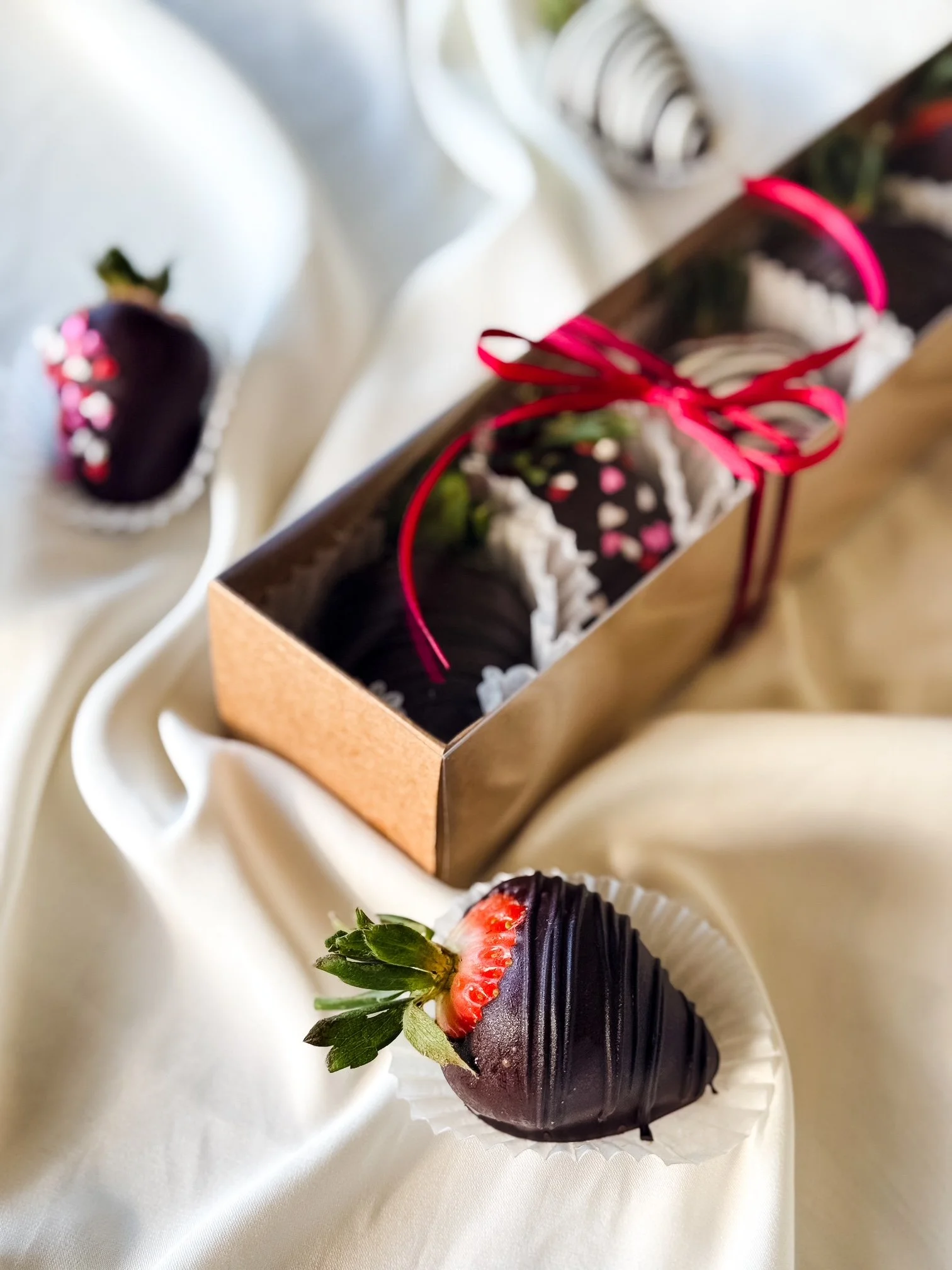 Chocolate-covered strawberries in a rectangular box with a red ribbon
