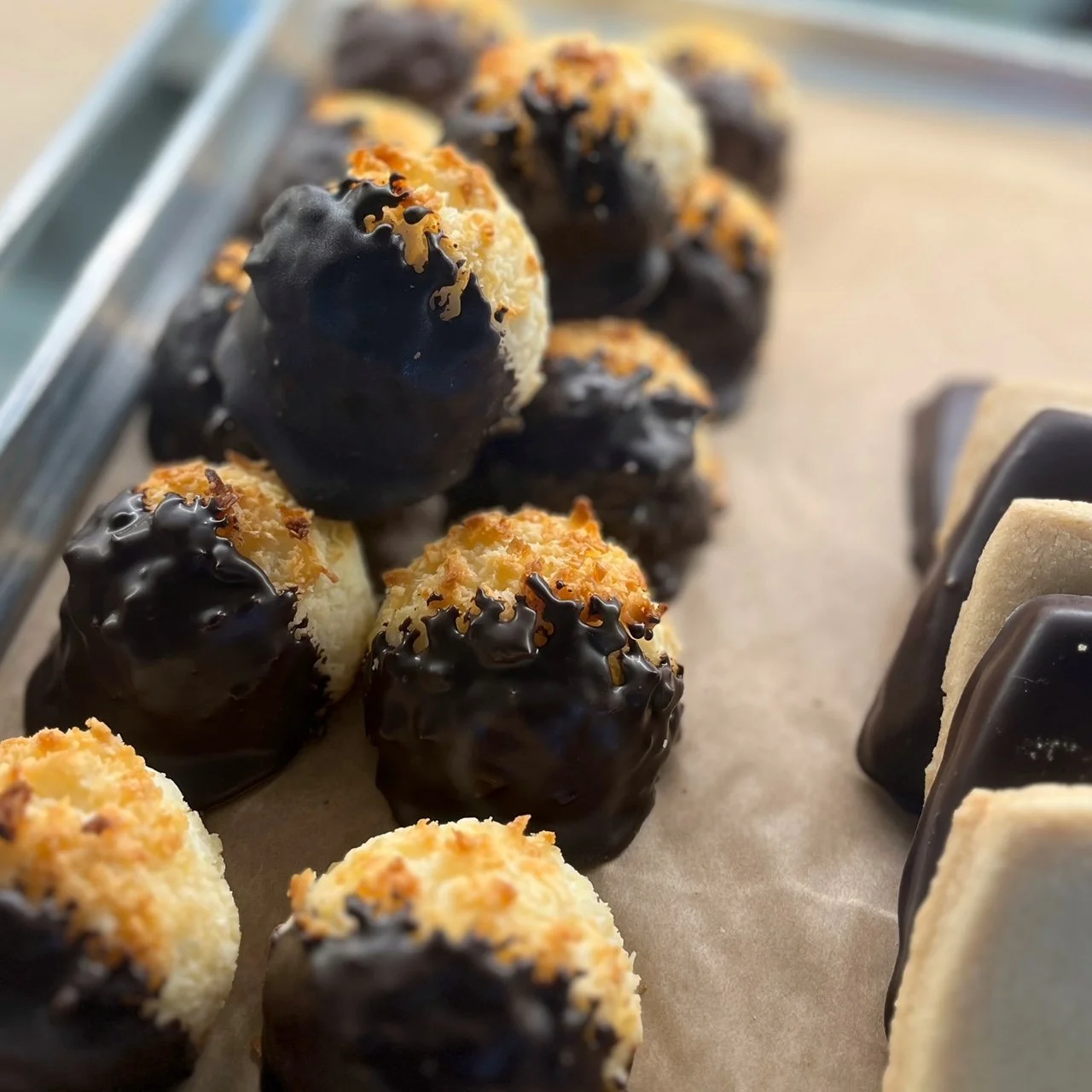 Close-up view of chocolate-dipped coconut macaroons on a baking sheet.