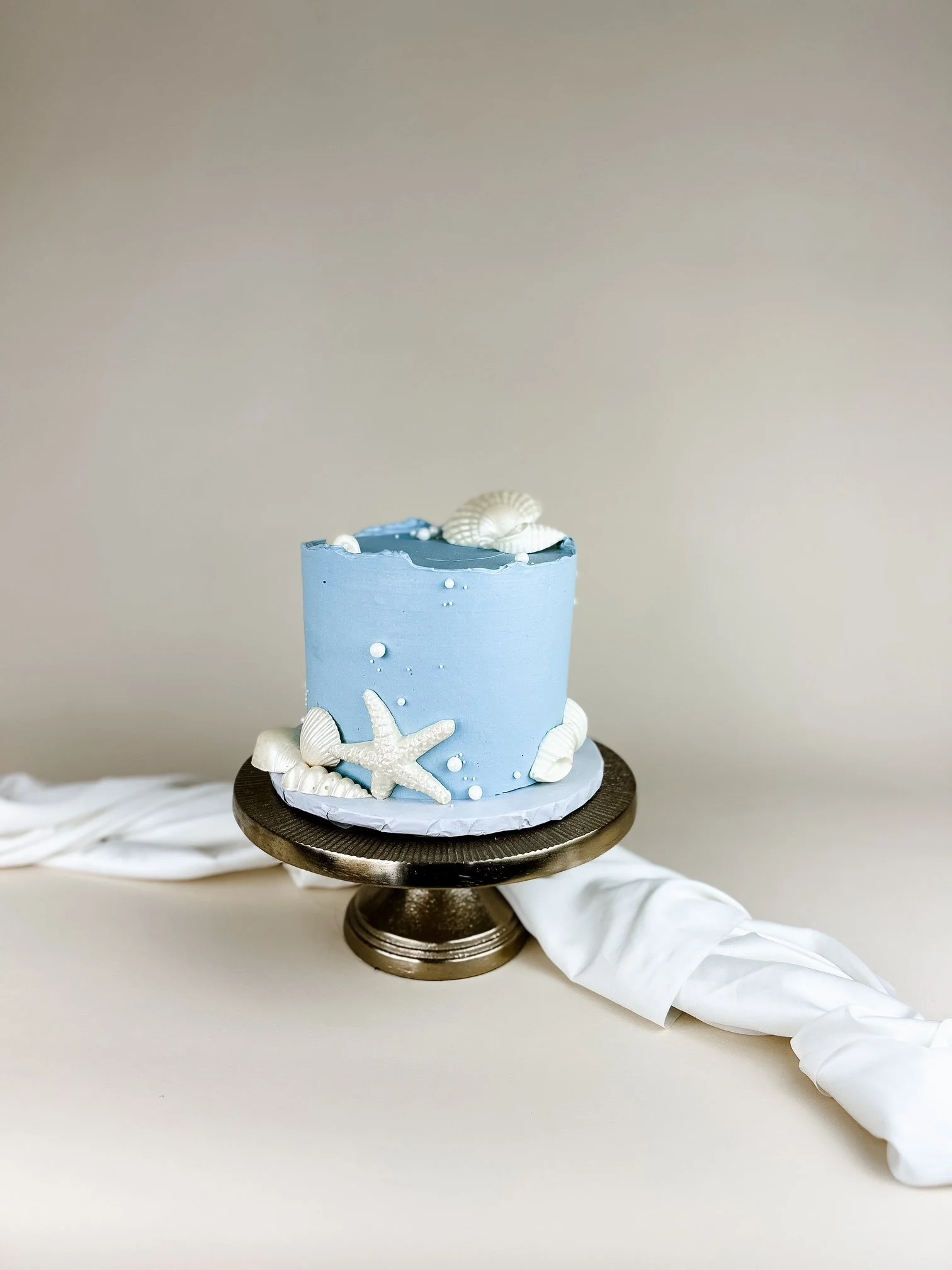 blue cake with white chocolate shells on satin cloth