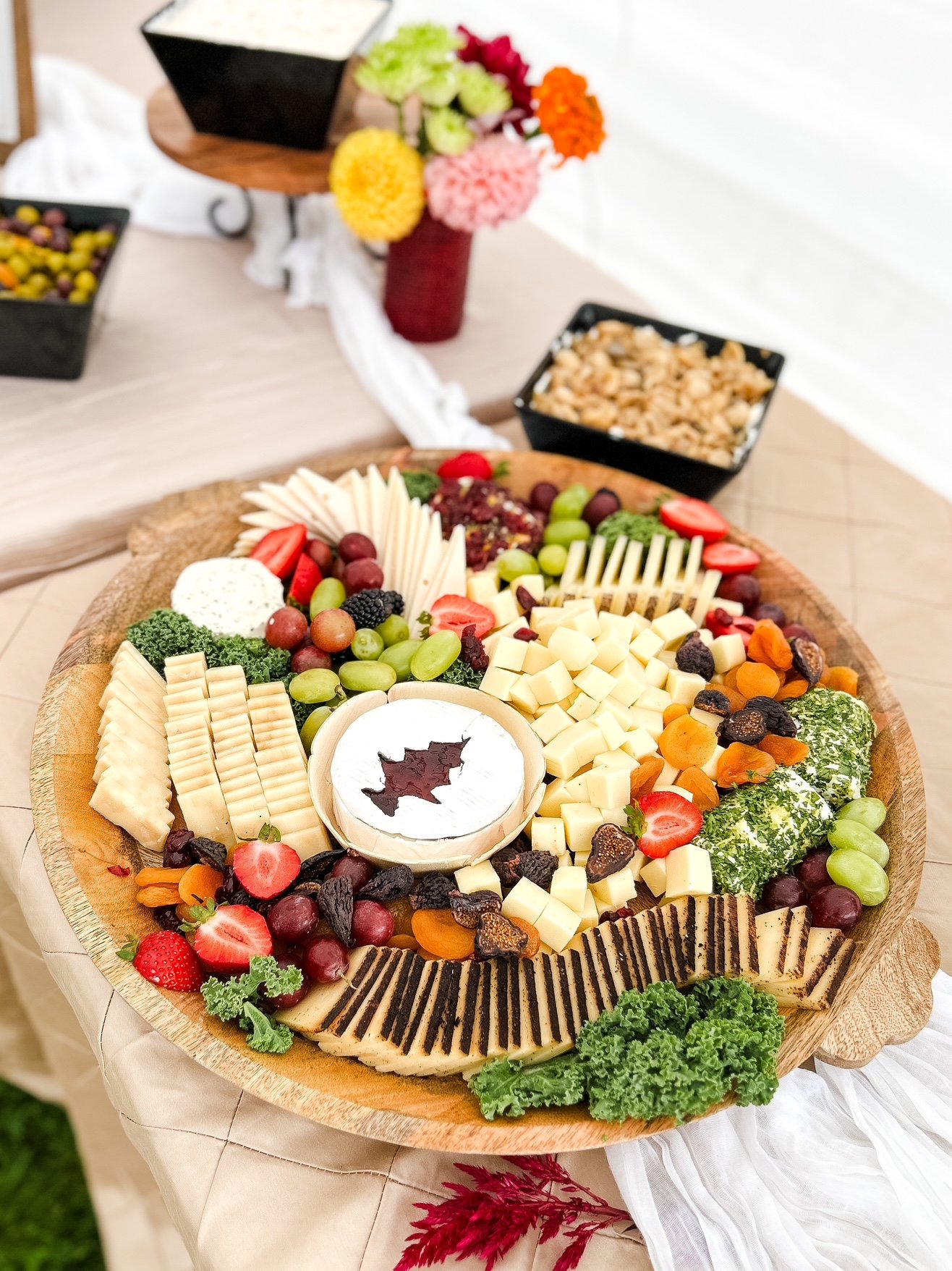 A large wooden tray with an assortment of cheeses and fruits